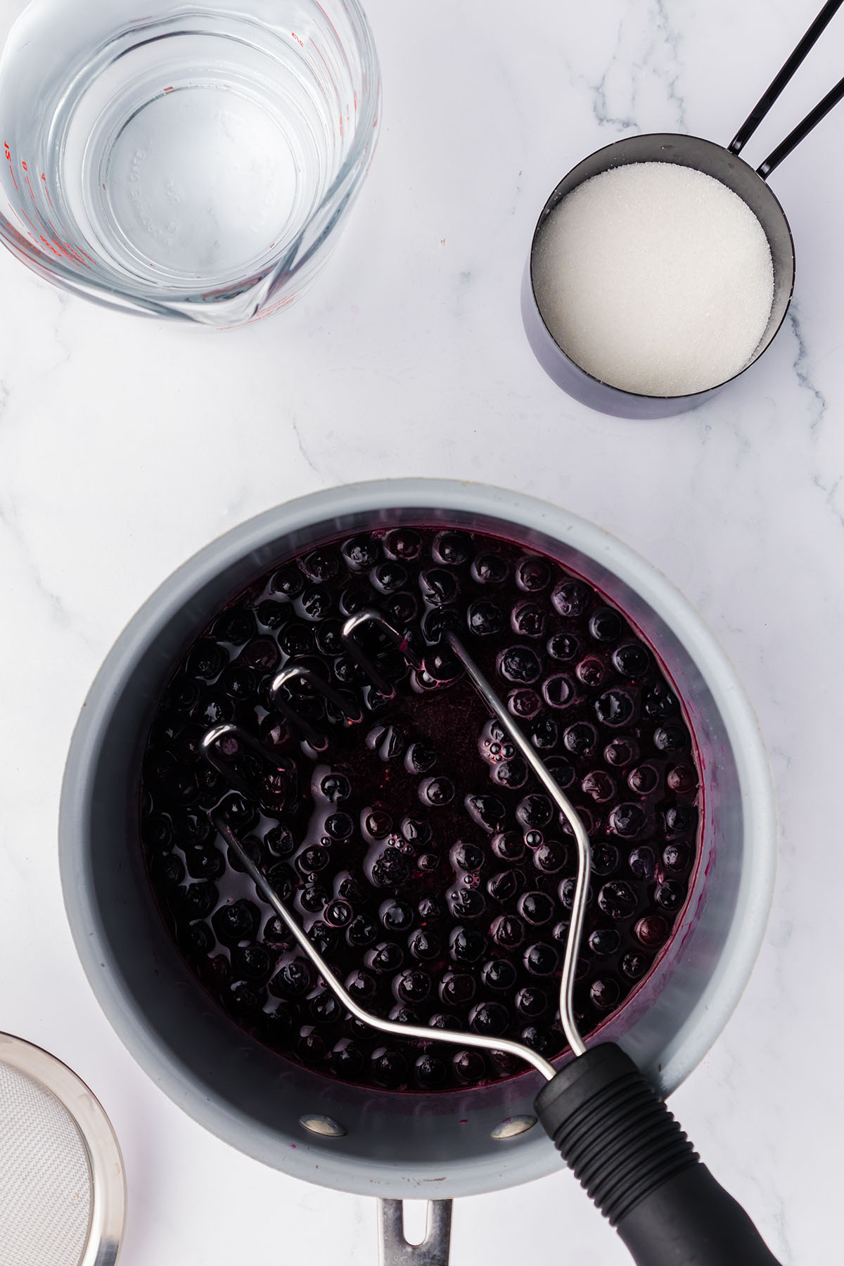 Mashing the blueberry mixture in the saucepan.