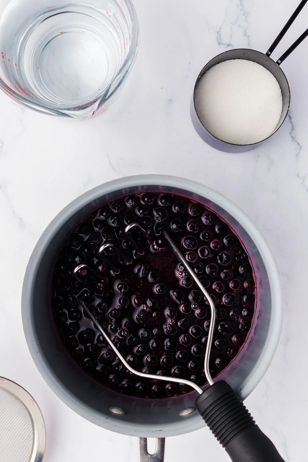 Mashing the blueberry mixture in the saucepan.