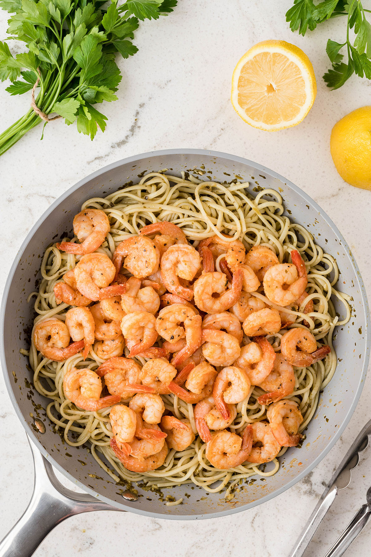 Seasoned shrimp is added to the pesto linguine in the skillet.