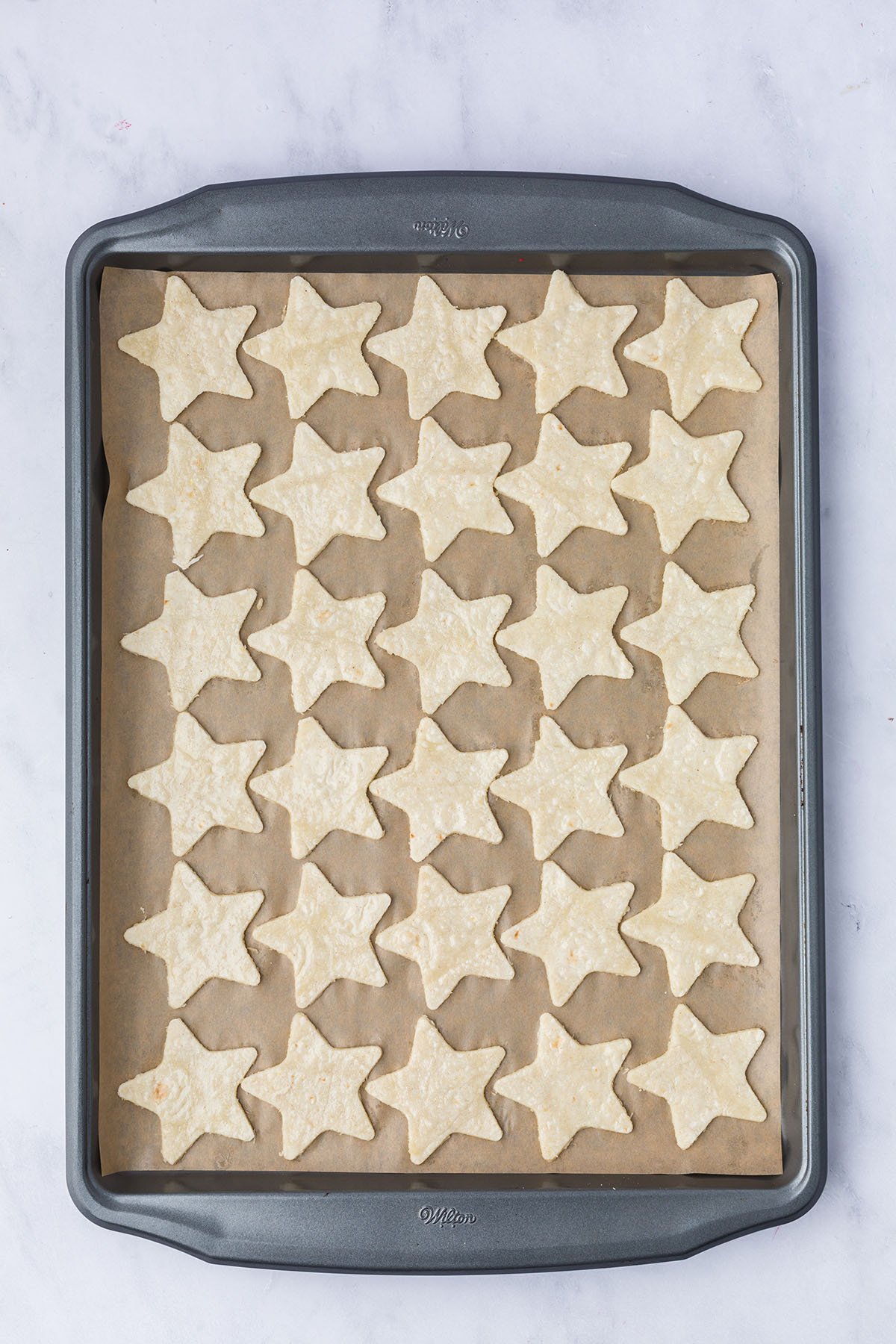 Star tortillas on a parchment paper lined baking pan.