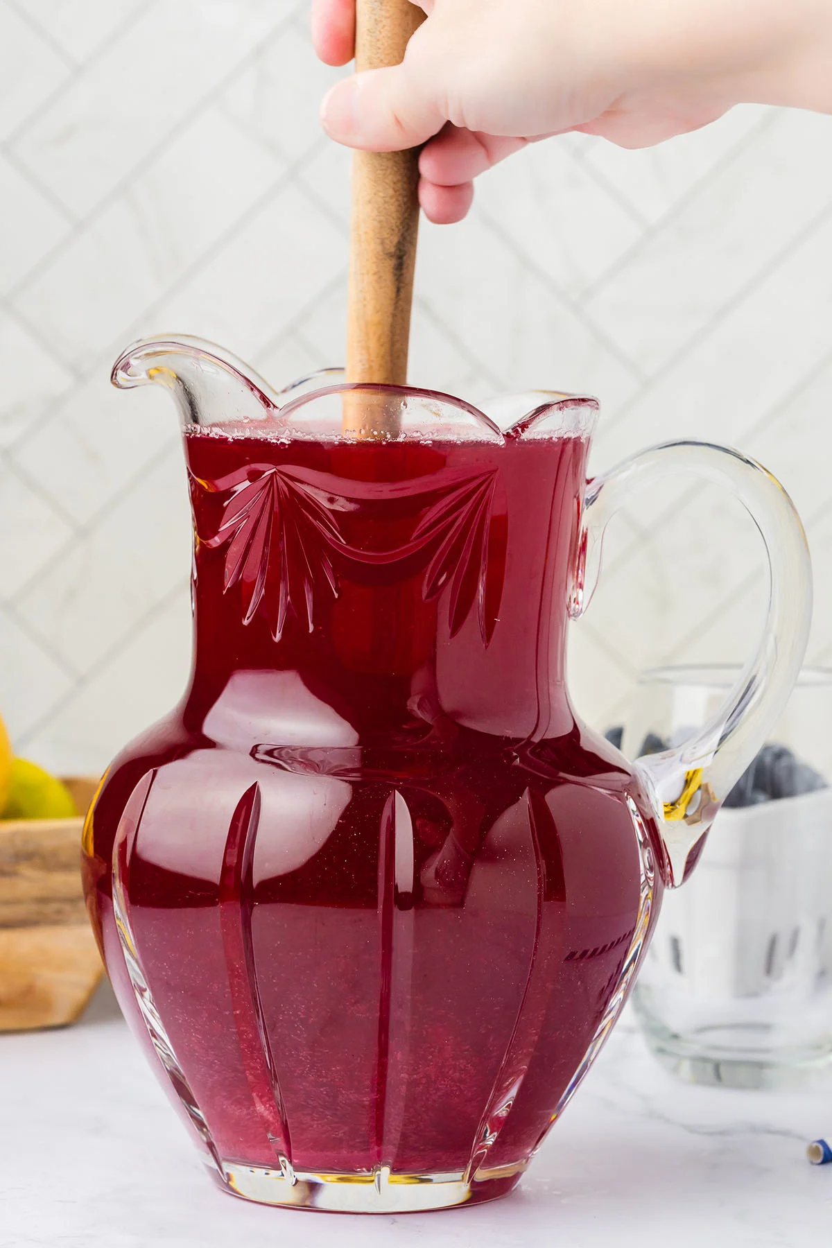 Stirring the blueberry lemonade in the glass pitcher.