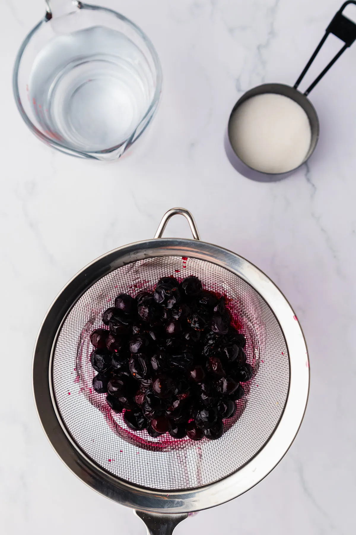 Straining blueberries through a mesh sieve.