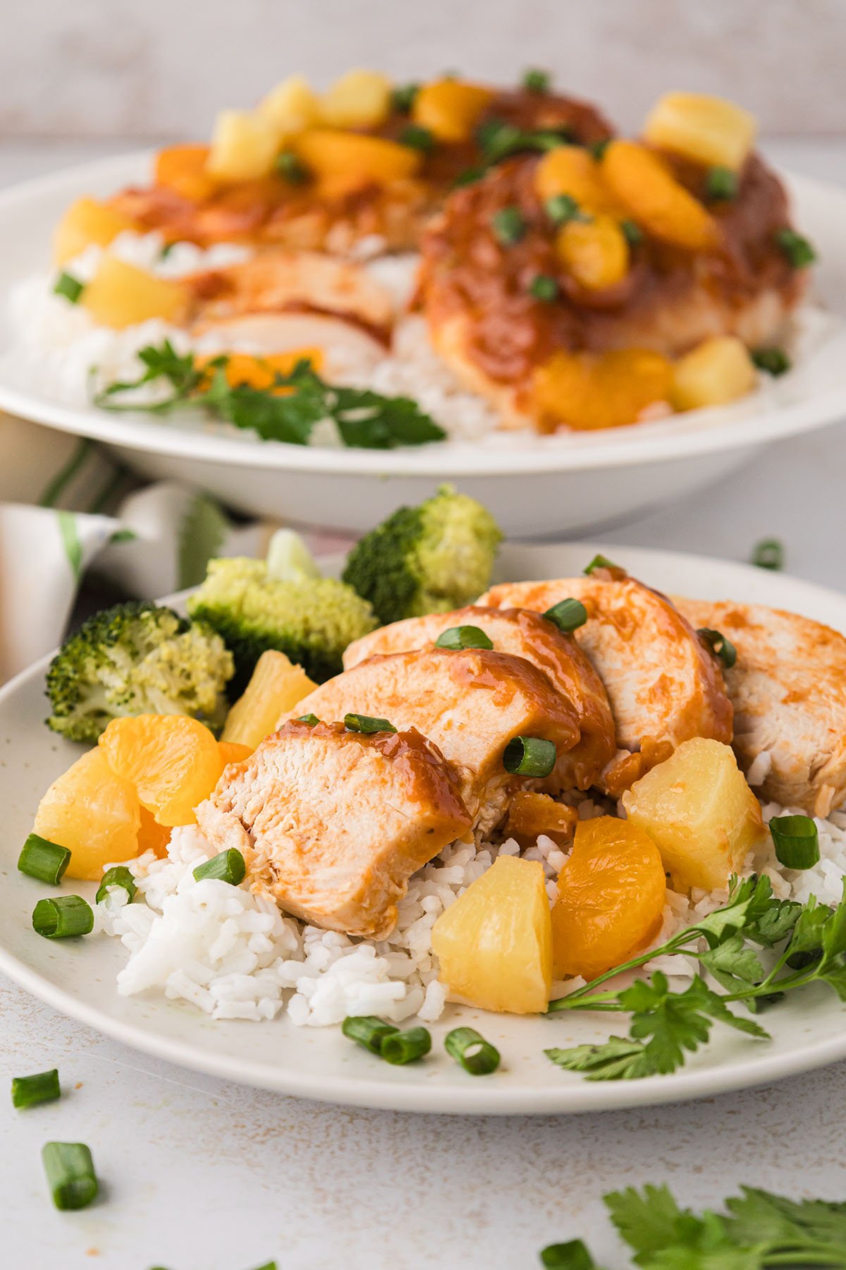 A sliced Hawaiian chicken breast served over rice with pineapple and broccoli on a plate.