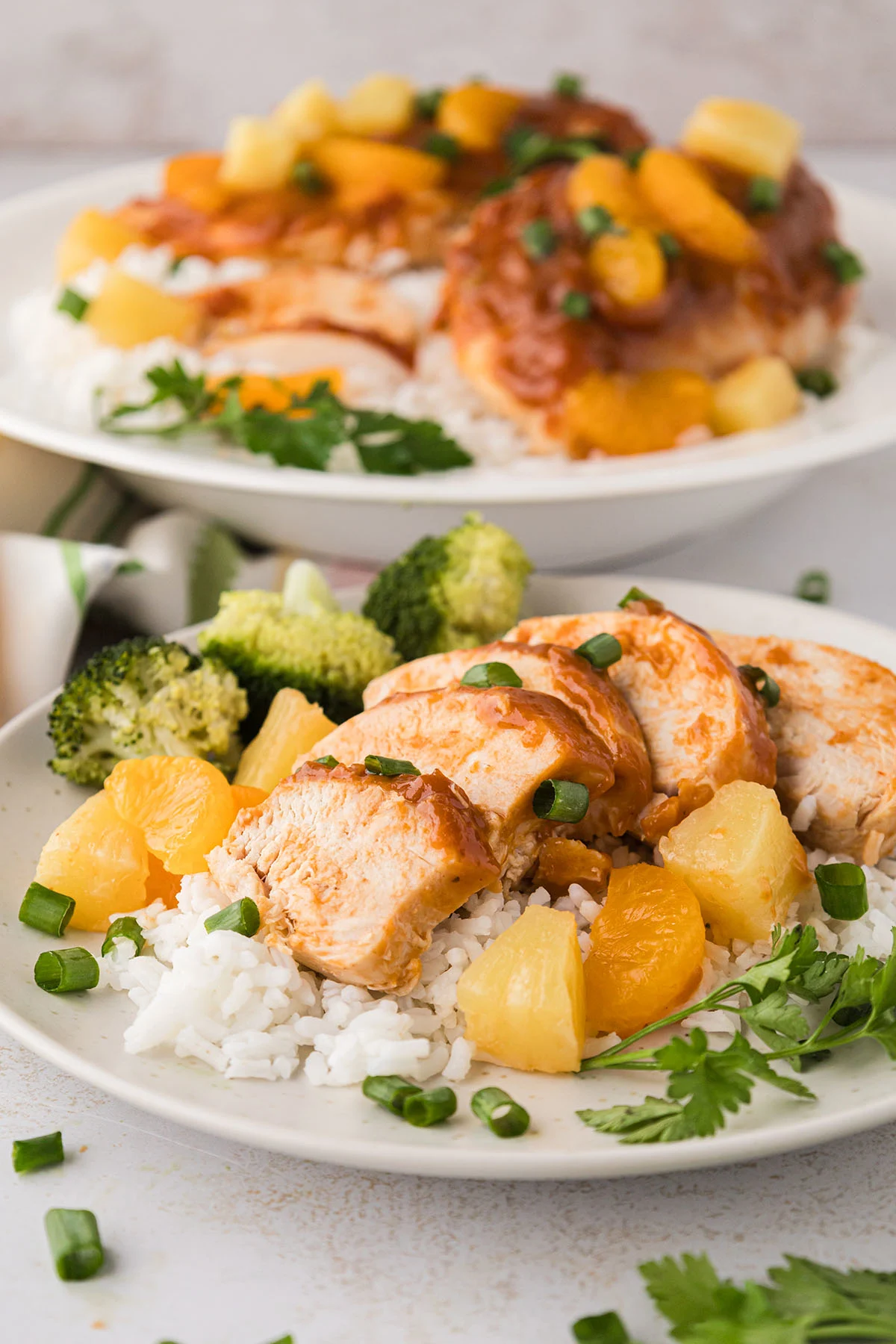 A sliced Hawaiian chicken breast served over rice with pineapple and broccoli on a plate.