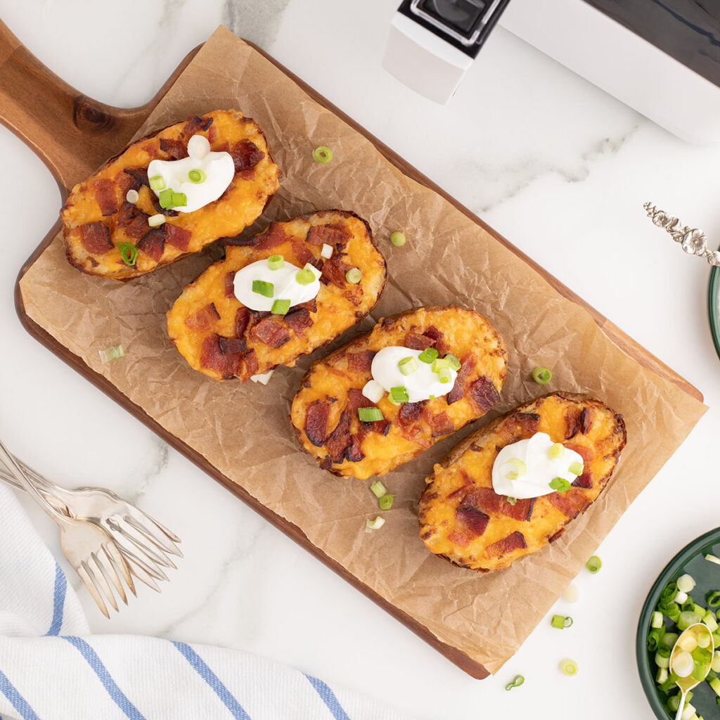 Air Fryer Twice Baked Potatoes on a parchment paper lined wooden serving board.