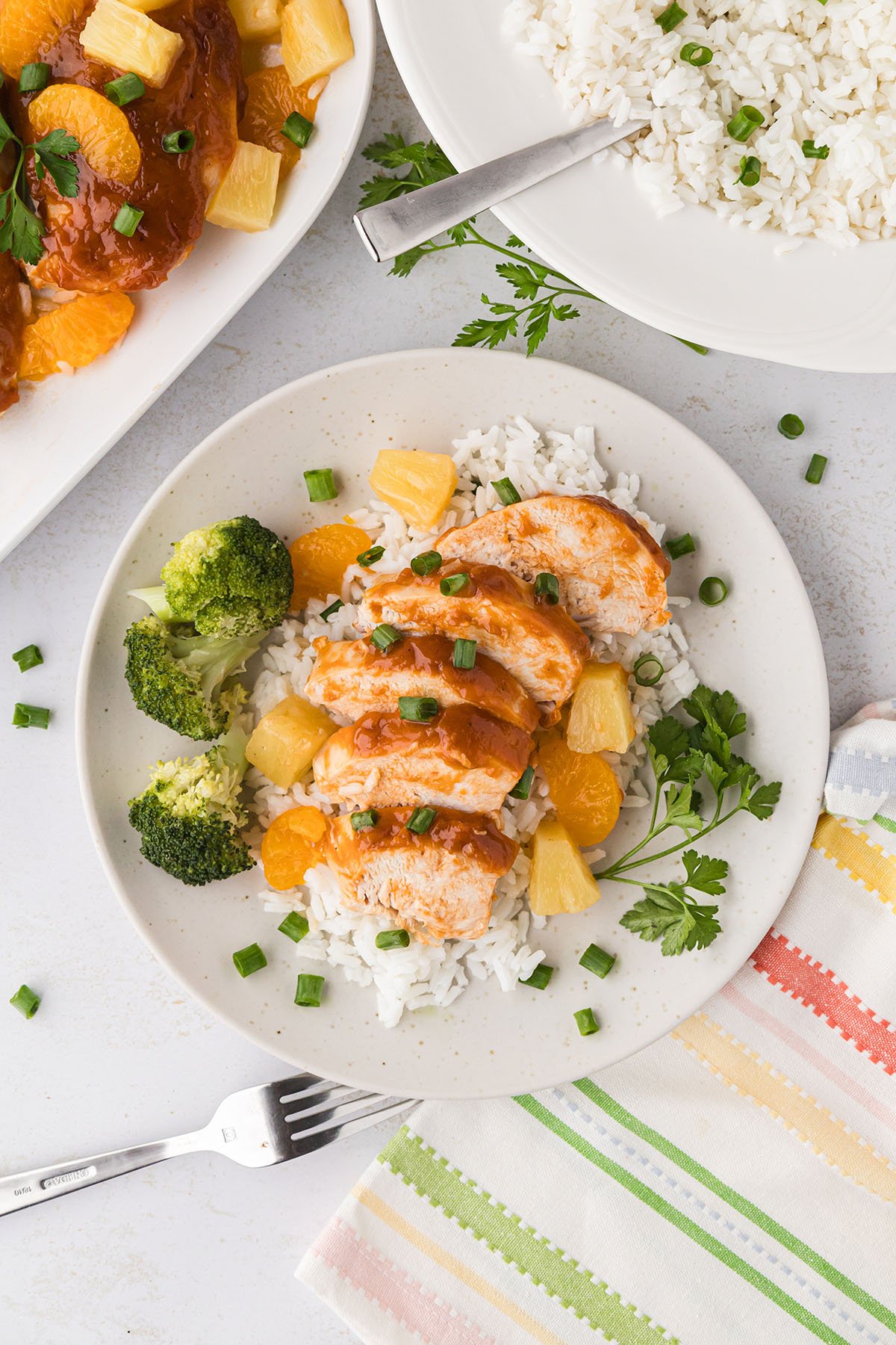 Sliced Hawaiian chicken served over rice with broccoli on a plate.