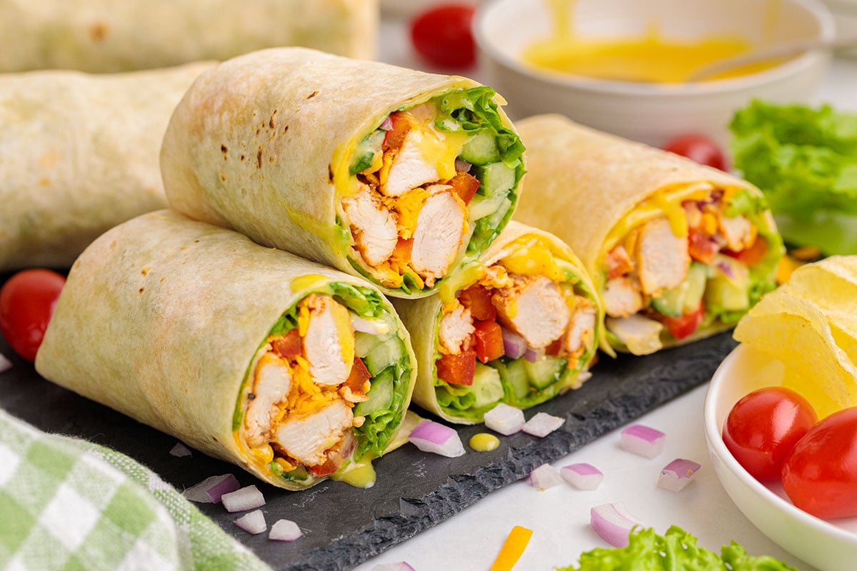 Honey Mustard Chicken Wraps sliced in half on a cutting board.
