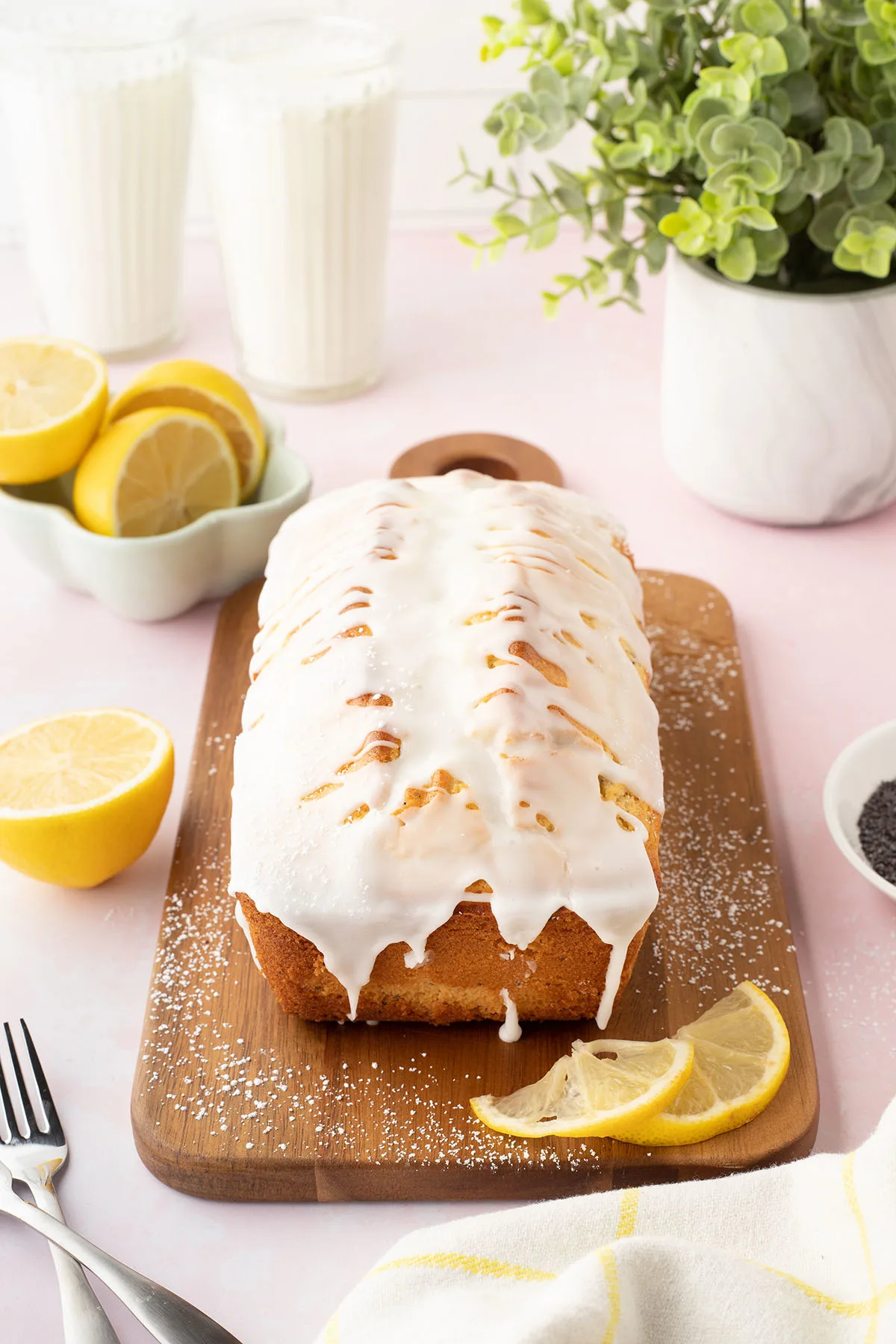 Lemon Poppy Seed Bread topped with Lemon Icing on a wooden serving board.