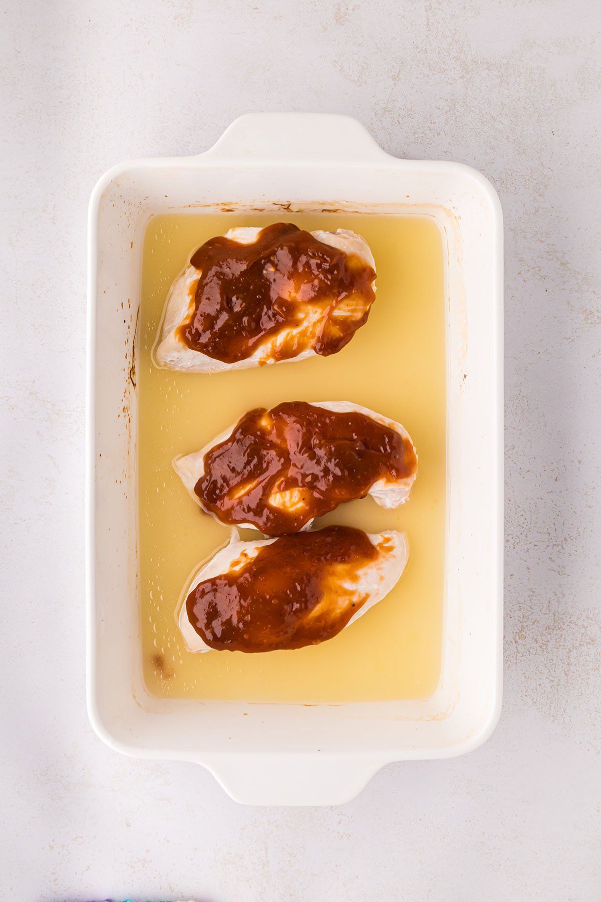 BBQ sauce was brushed over the baked chicken in the baking pan.