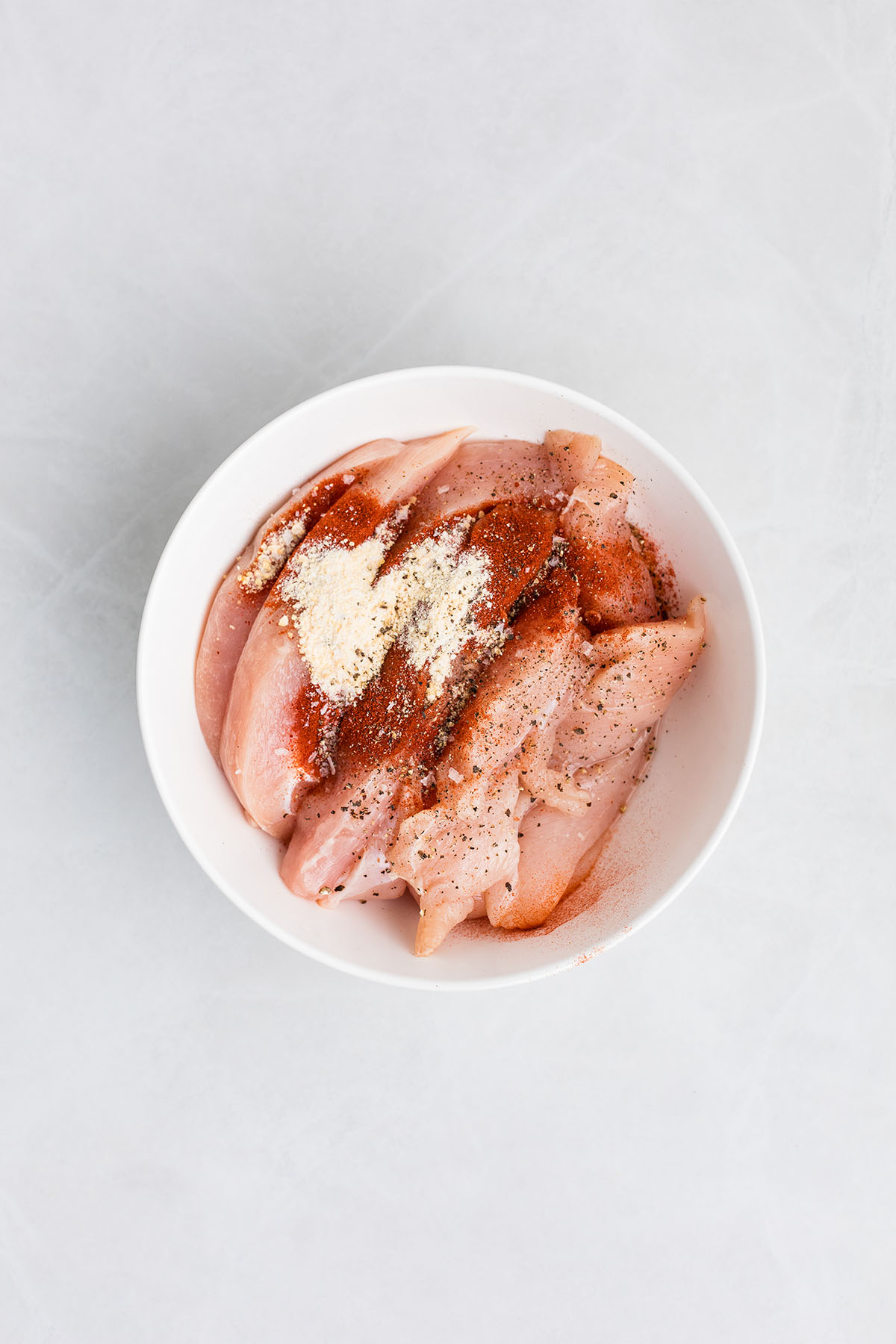 Chicken, garlic powder, smoked paprika, salt, and pepper in a bowl.