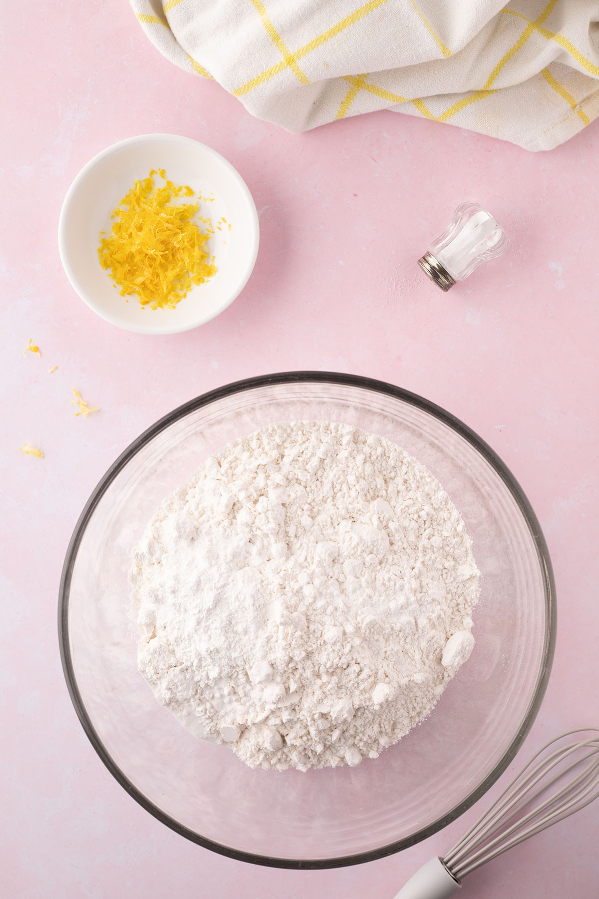 A glass bowl filled with dry ingredients, including flour, baking powder, baking soda, and salt.