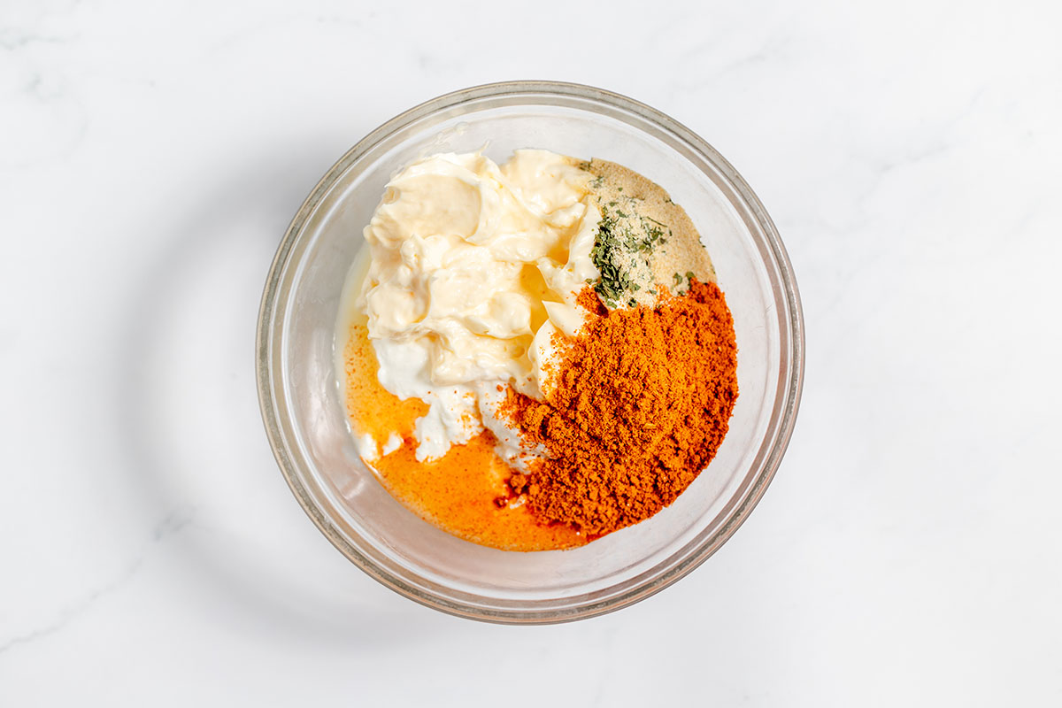 Mayonnaise, sour cream, lime juice, taco seasoning, onion powder, and parsley in  a mixing bowl.