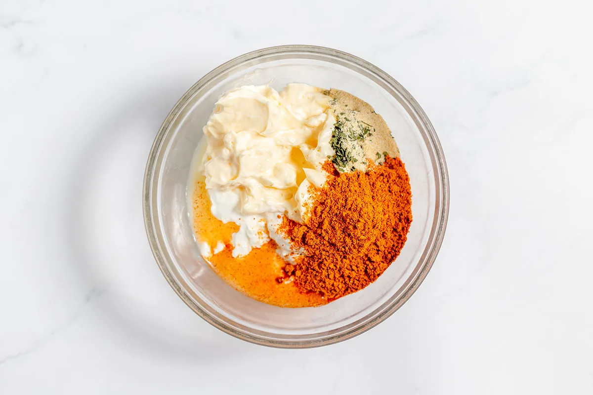 Mayonnaise, sour cream, lime juice, taco seasoning, onion powder, and parsley in  a mixing bowl.