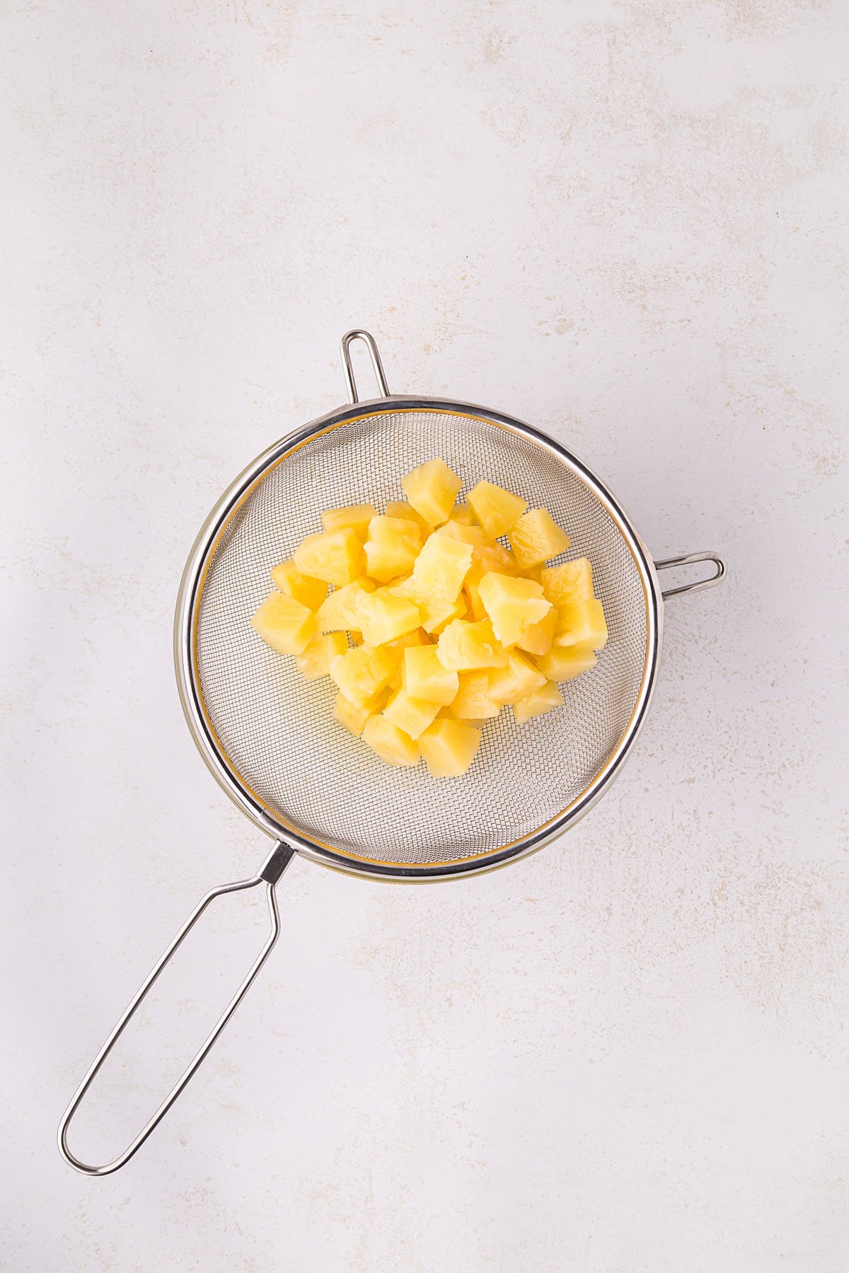 Pineapple chunks in a strainer.