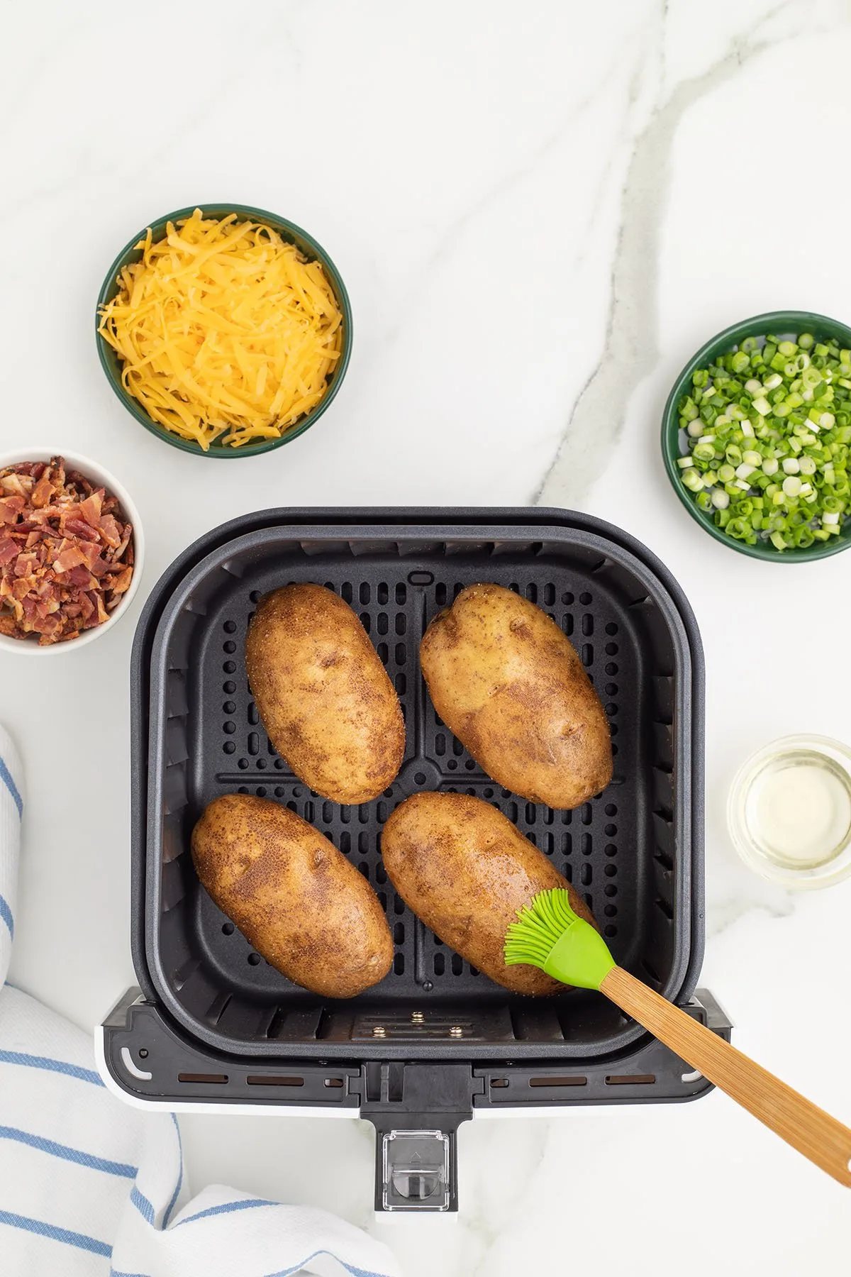 Whole potatoes brushed with oil and sprinkled with salt in the air fryer.