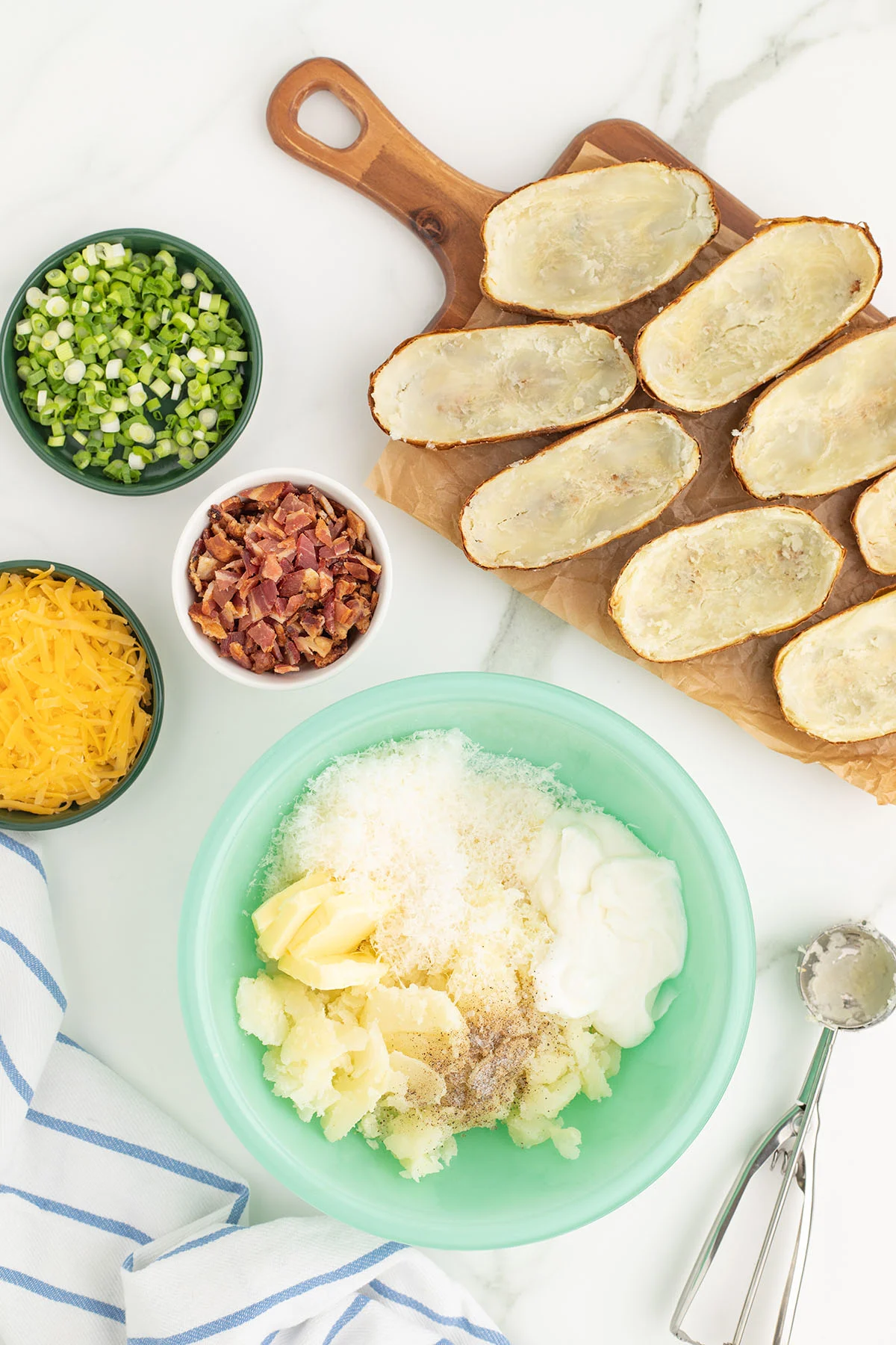 Potatoes, butter, sour cream, half-and-half, Parmesan cheese, salt, and pepper in a mixing bowl.