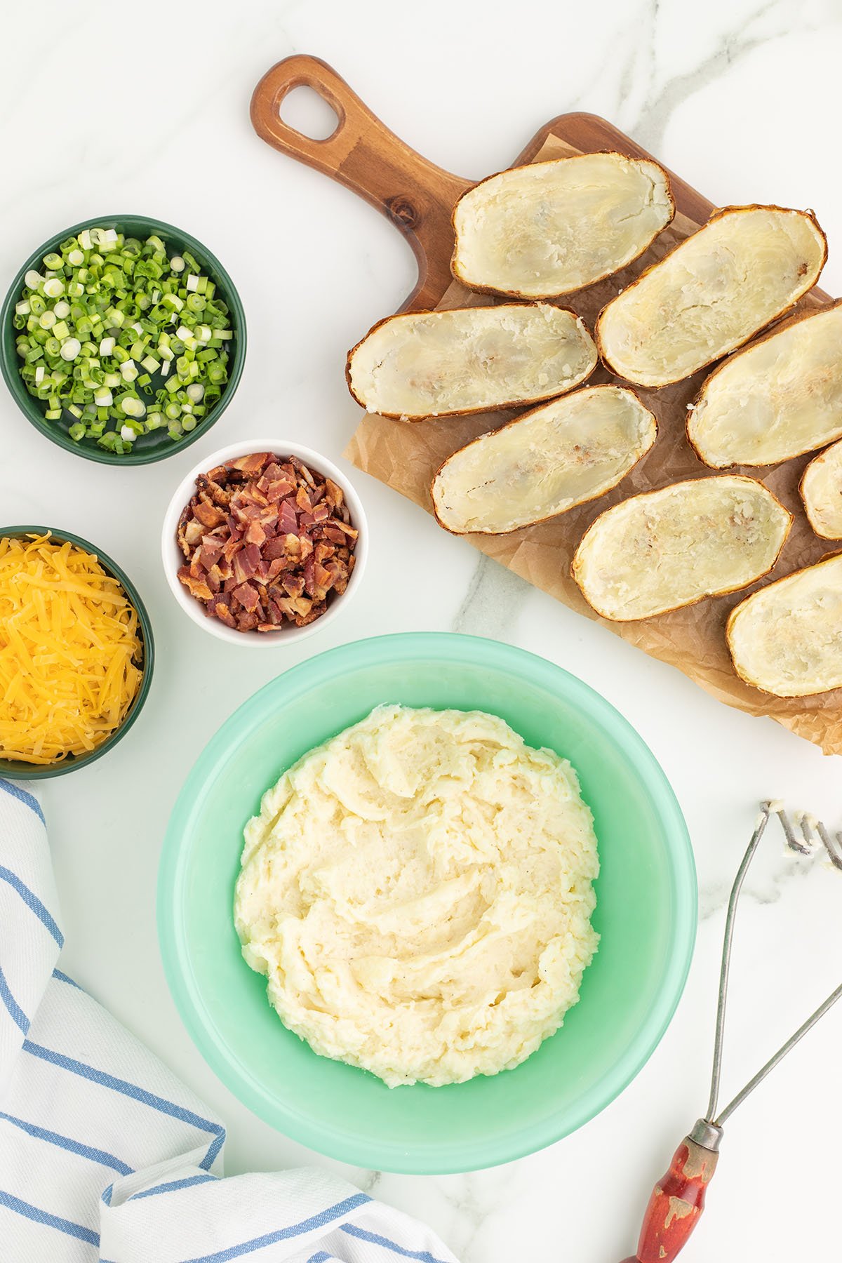 Potatoes are mashed with butter, sour cream, half and half, Parmesan cheese, salt, and pepper in a mixing bowl.