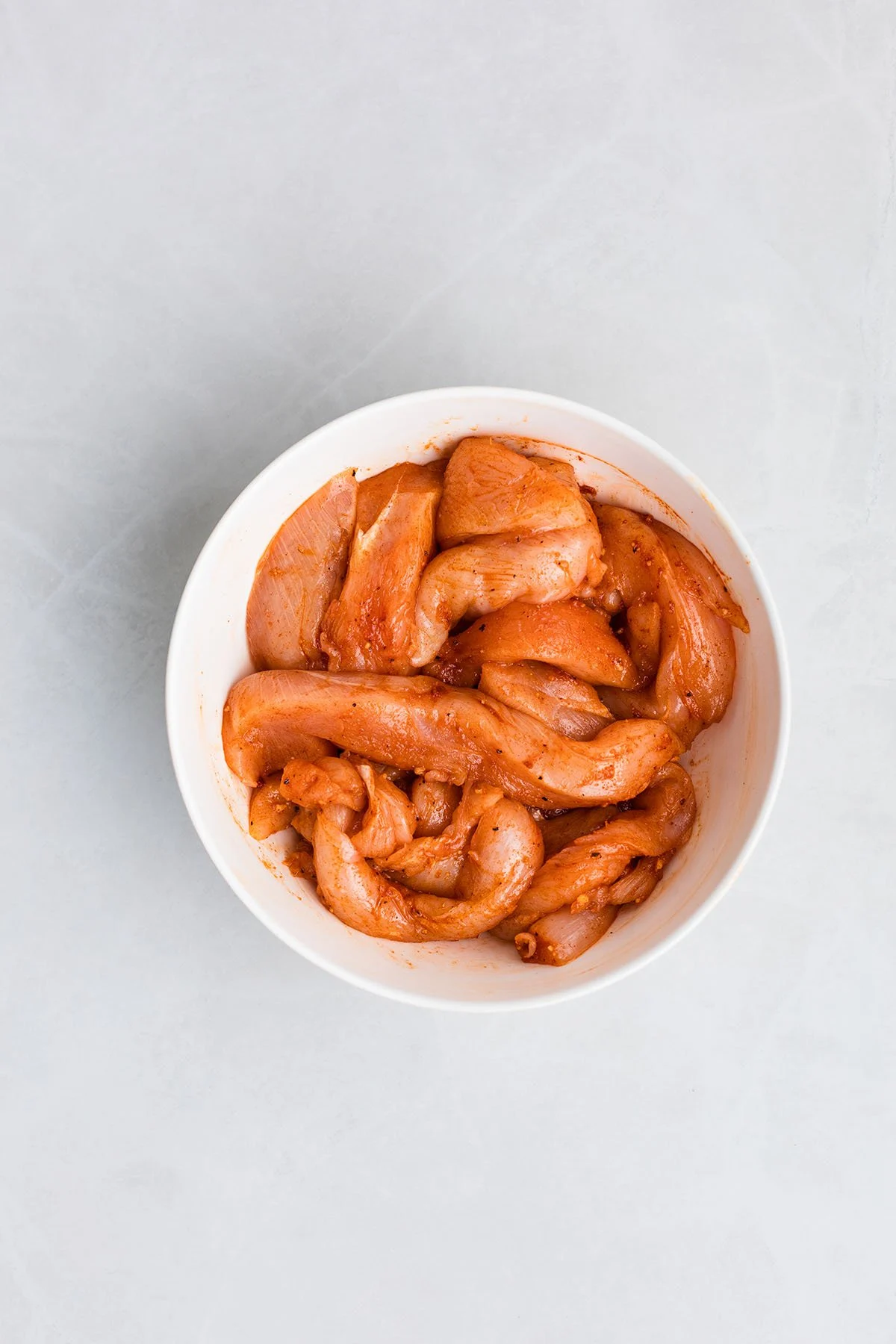 Seasoned raw chicken in a bowl.