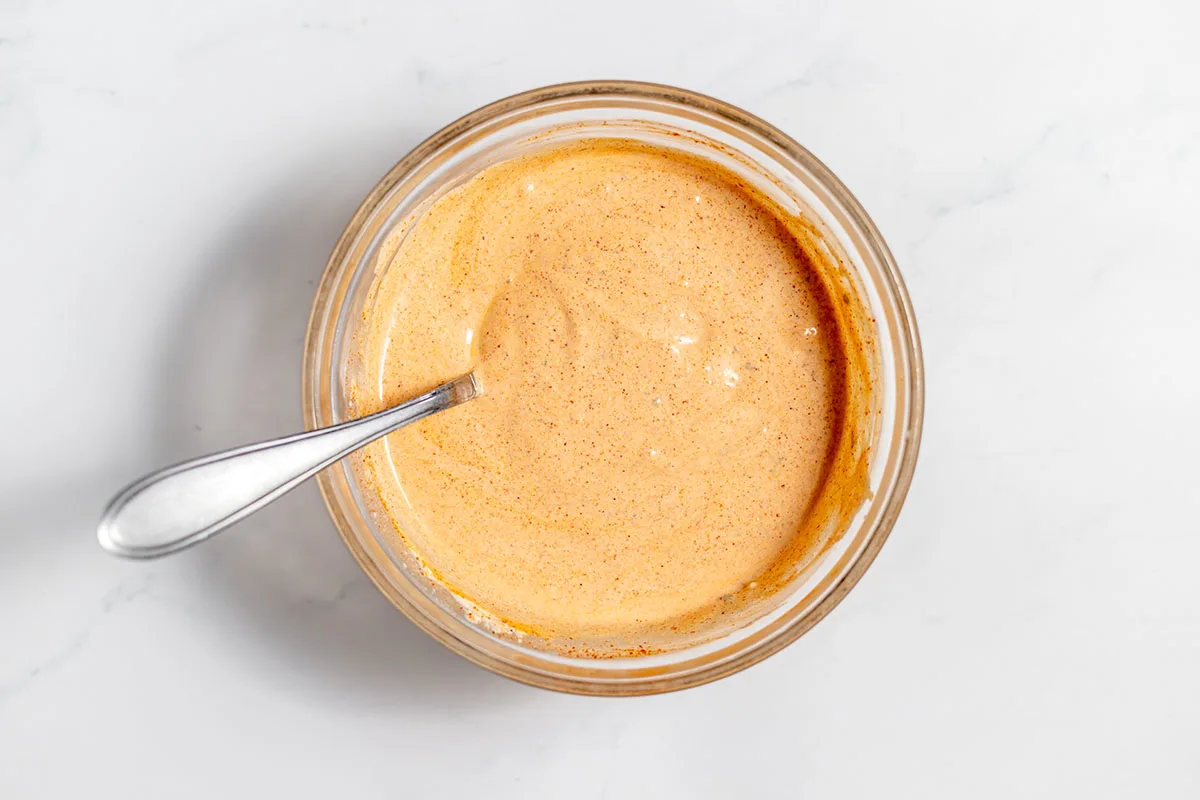 Southwest chicken salad dressing is mixed in a glass mixing bowl.
