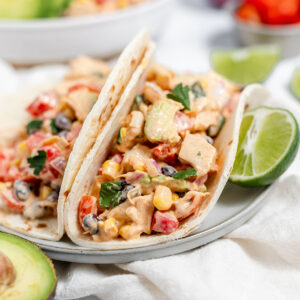 Southwest chicken salad tacos on a white plate with a slice of lime.