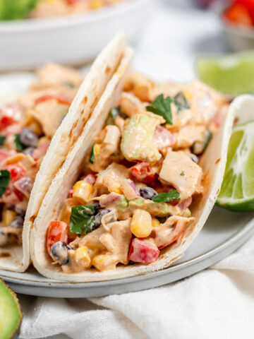 Southwest chicken salad tacos on a white plate with a slice of lime.