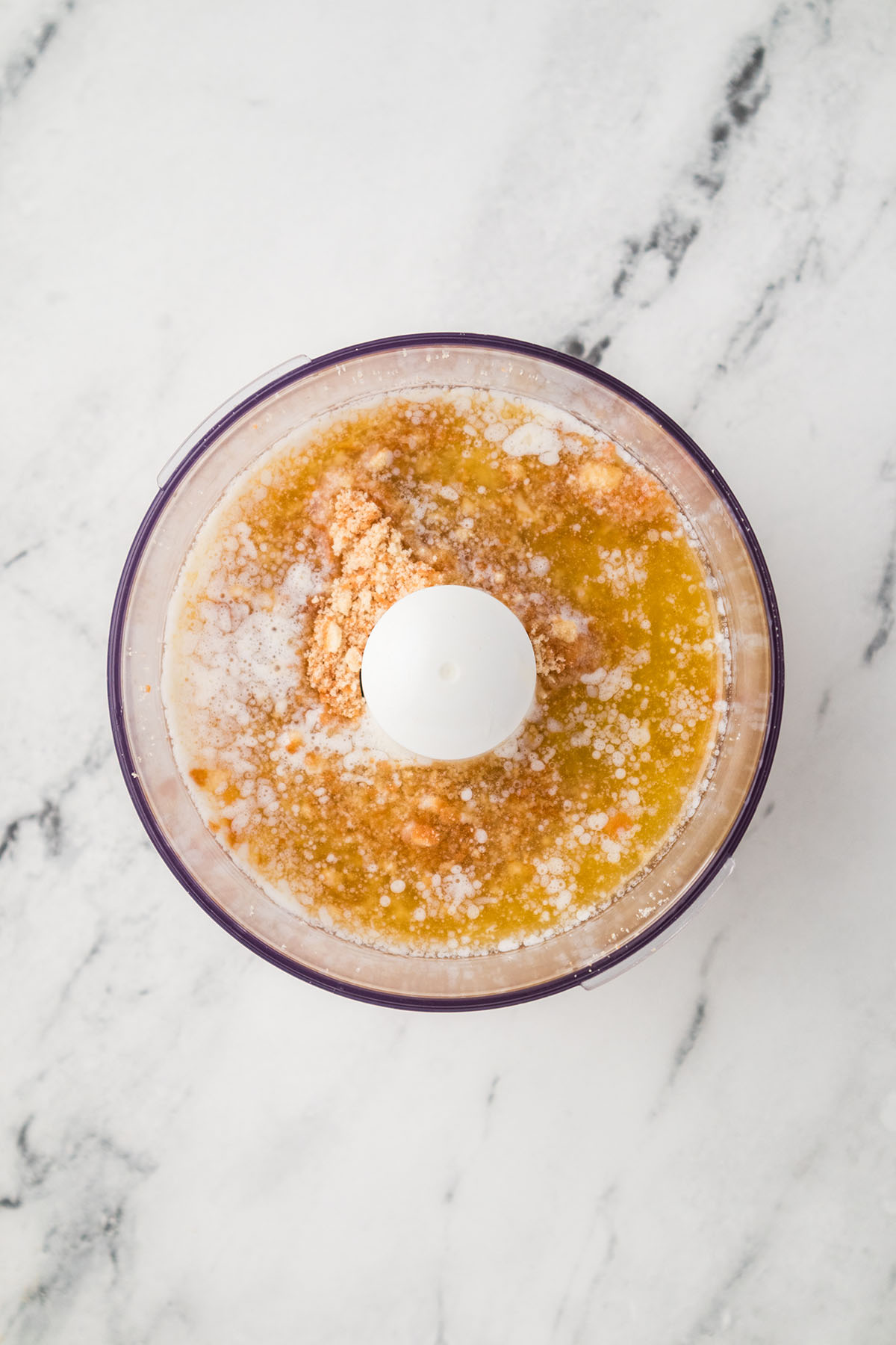 Vanilla wafer crumbs are mixed with butter in the food processor.