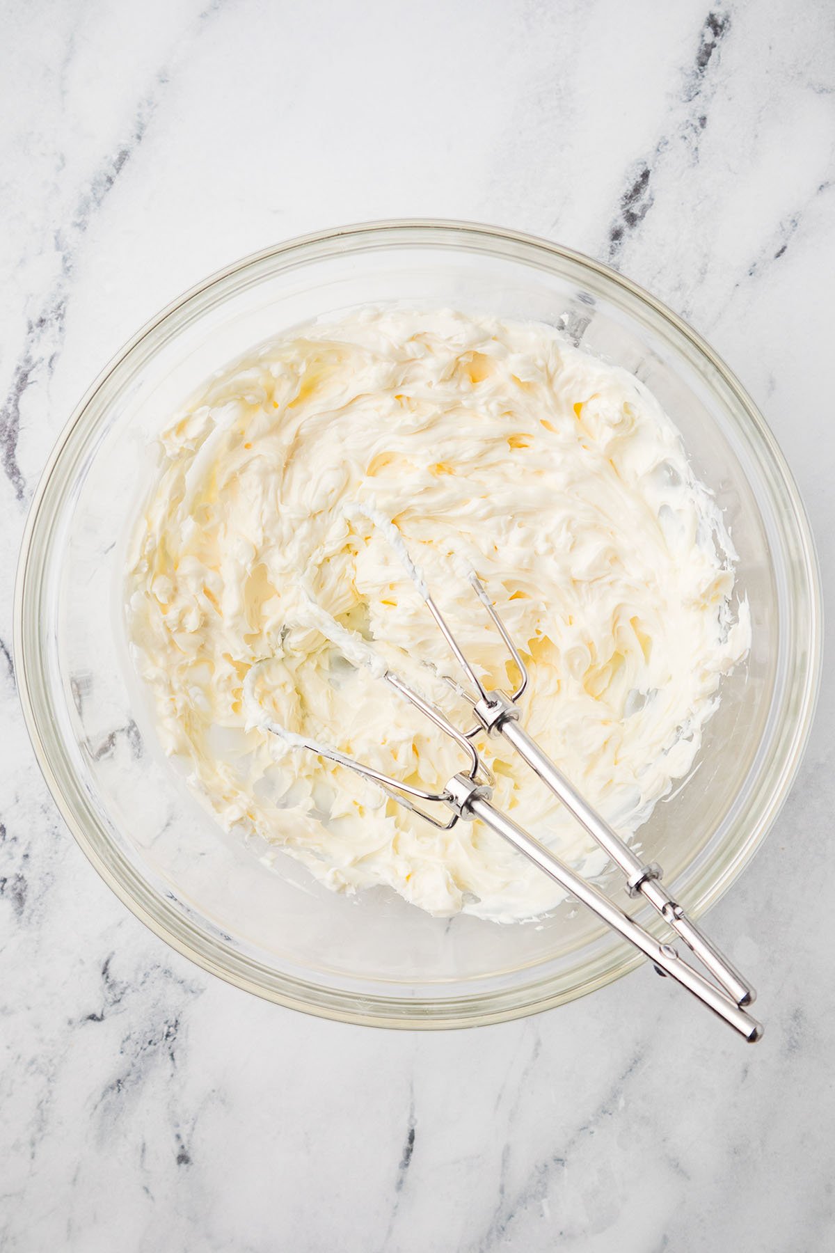 Whipped cream cheese in a glass mixing bowl.