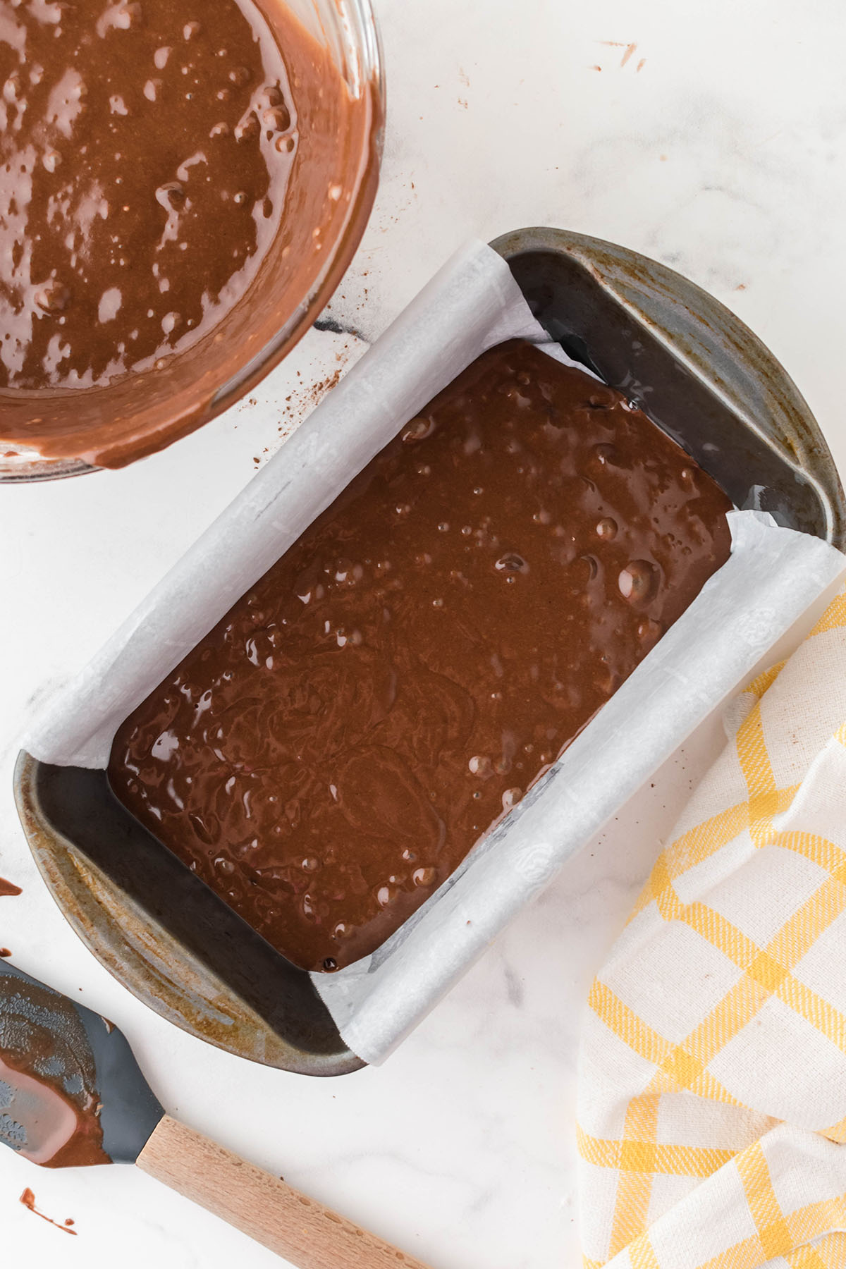 Chocolate Loaf Cake batter poured in a parchment paper lined baking pan.