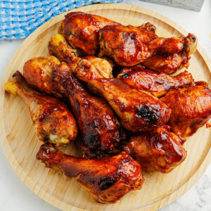 BBQ Chicken Drumsticks on a wooden serving board.