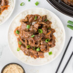 Mongolian Beef served over rice on a plate.