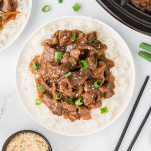 Mongolian Beef served over rice on a plate.
