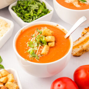 Creamy Tomato Soup in a white bowl topped with croutons.