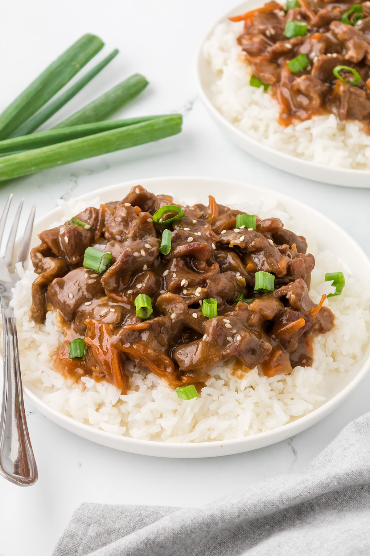 Mongolian Beef served over rice on a white plate.