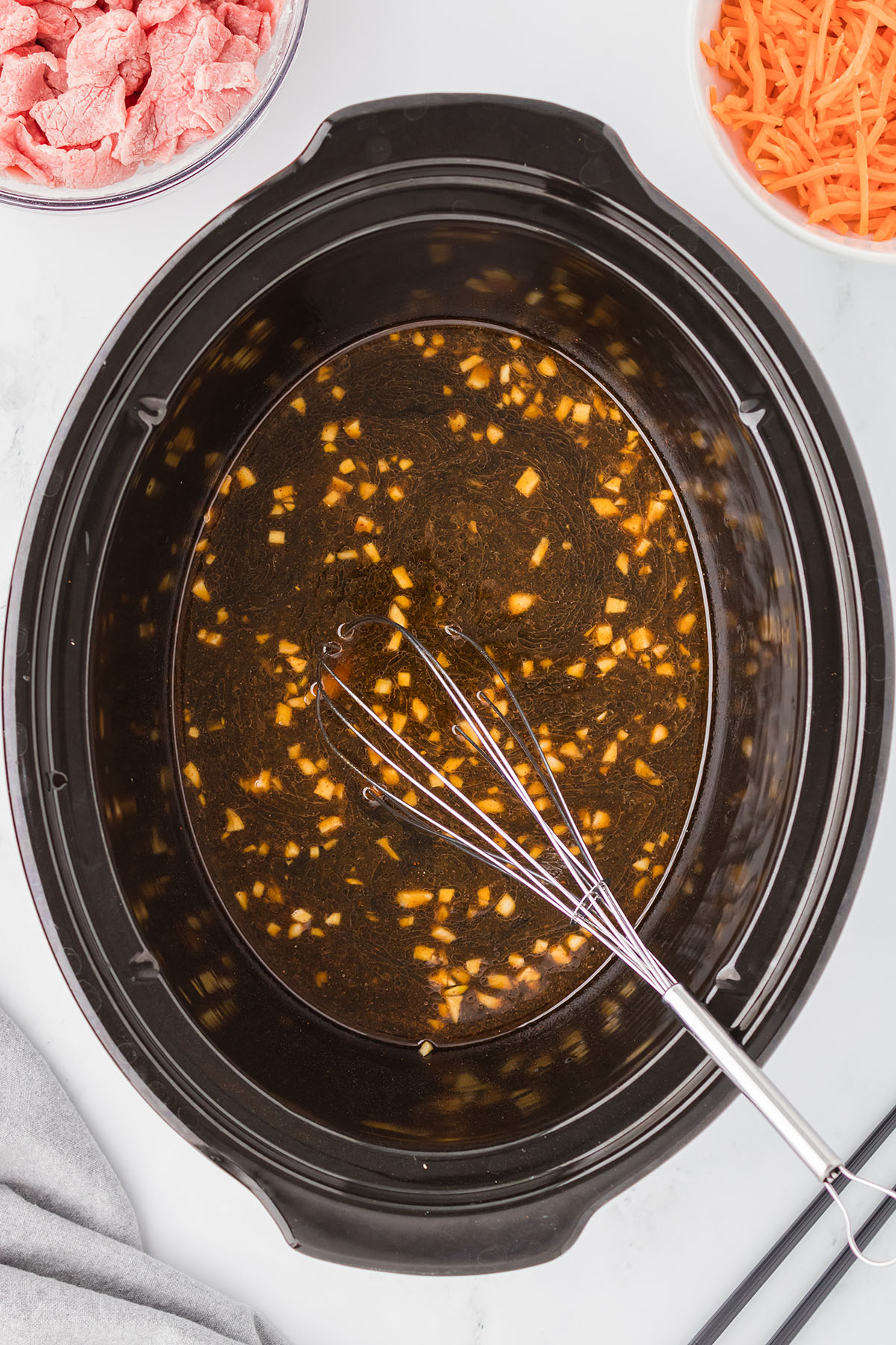 Beef broth, soy sauce, brown sugar, sesame oil, ginger, minced garlic, and chili powder whisked in slow cooker.