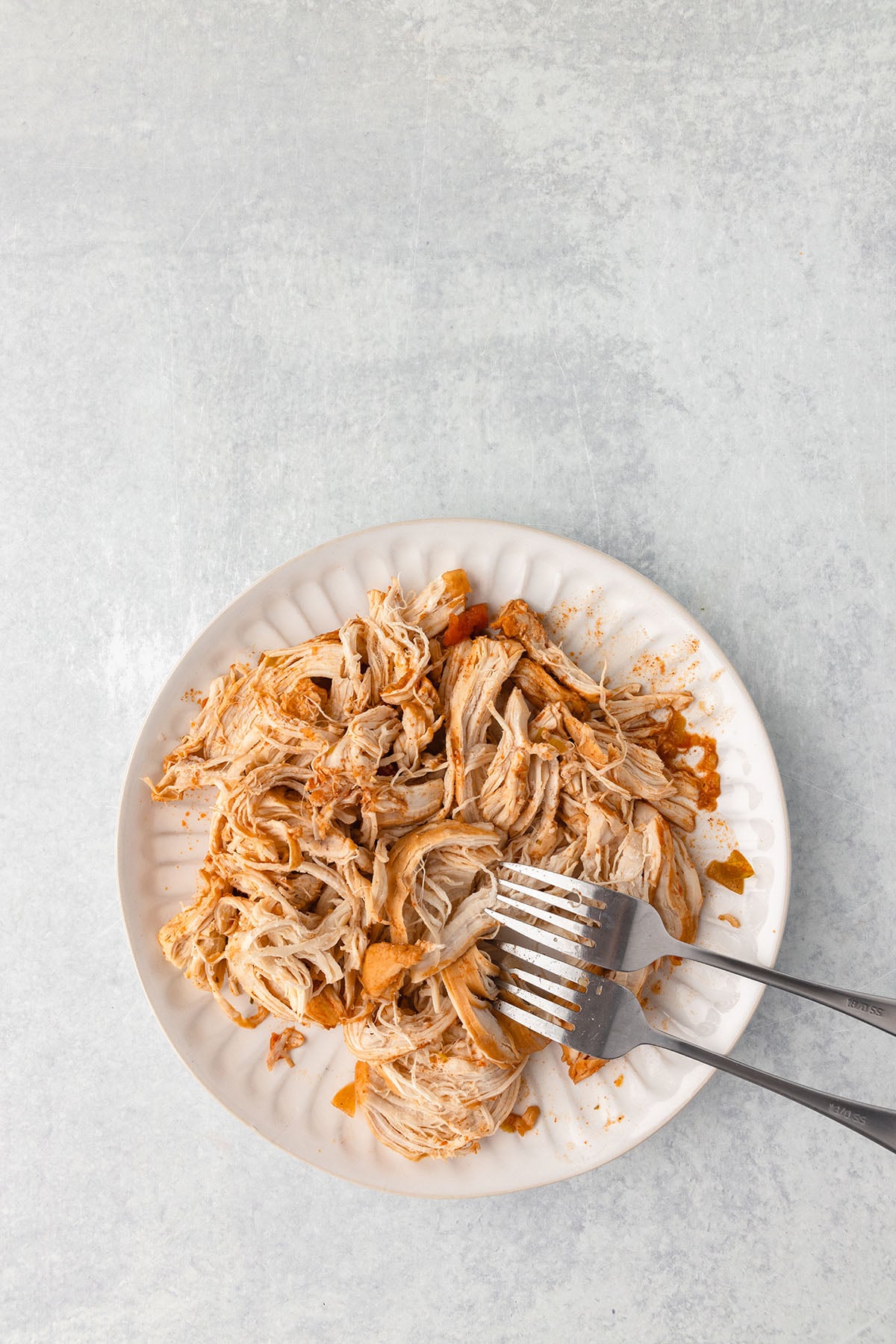 Chicken is shredded on a plate with forks.