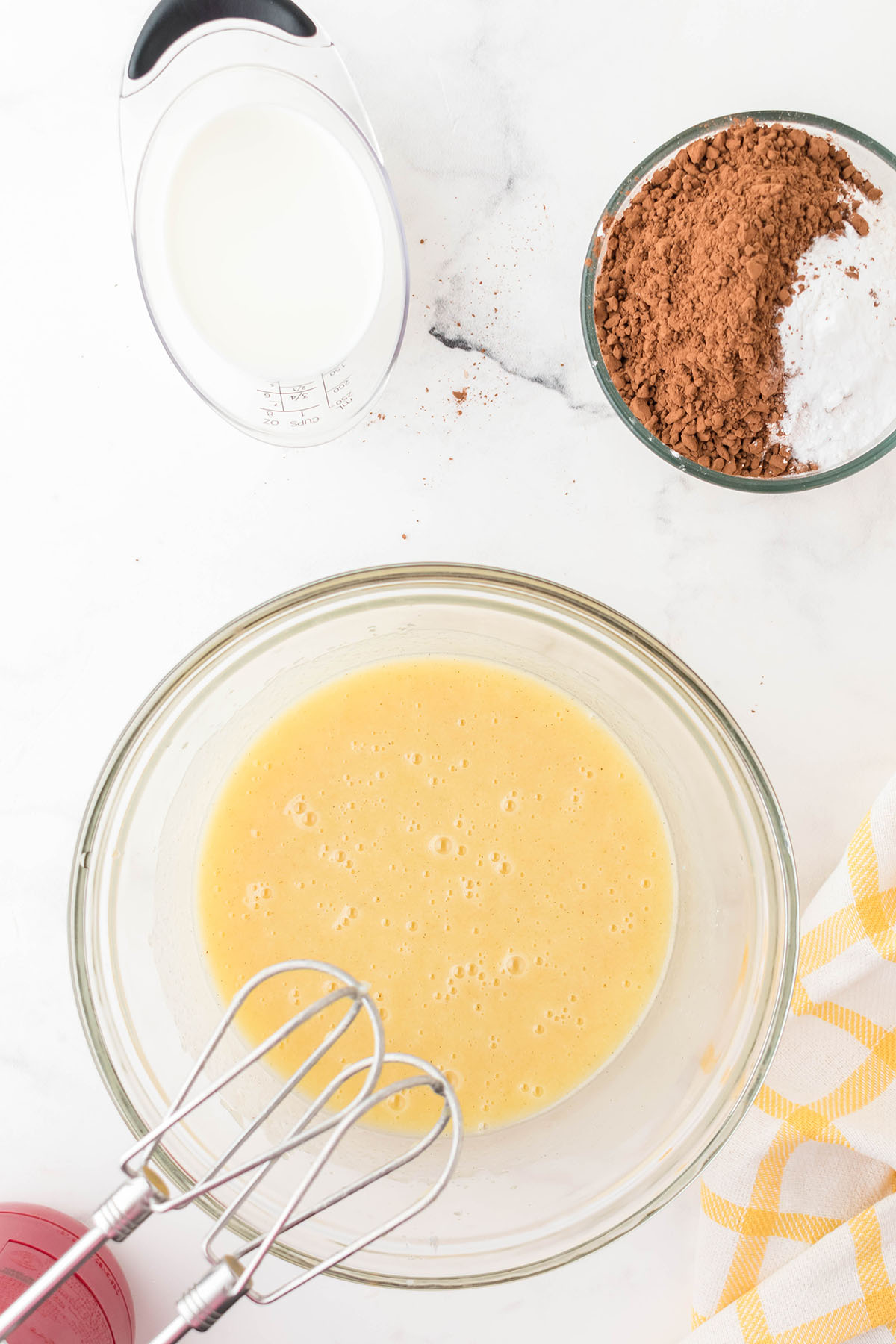 Eggs added to the vegetable oil, sugar, and sour cream in the glass mixing bowl.