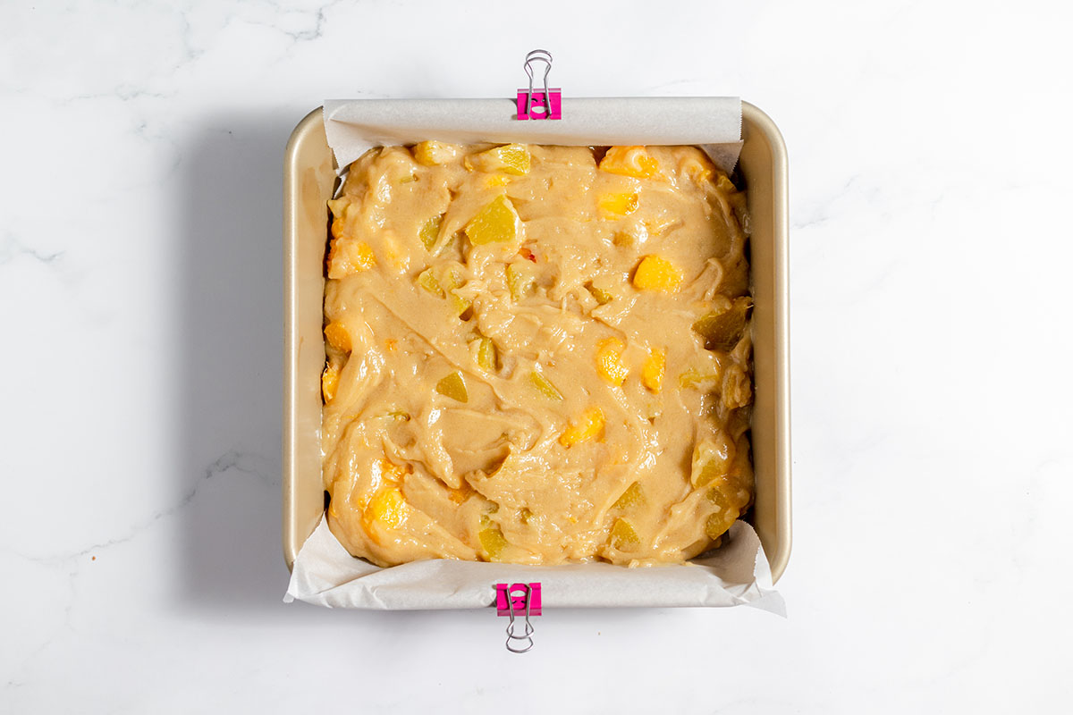 Peach coffee cake batter in a square baking pan.