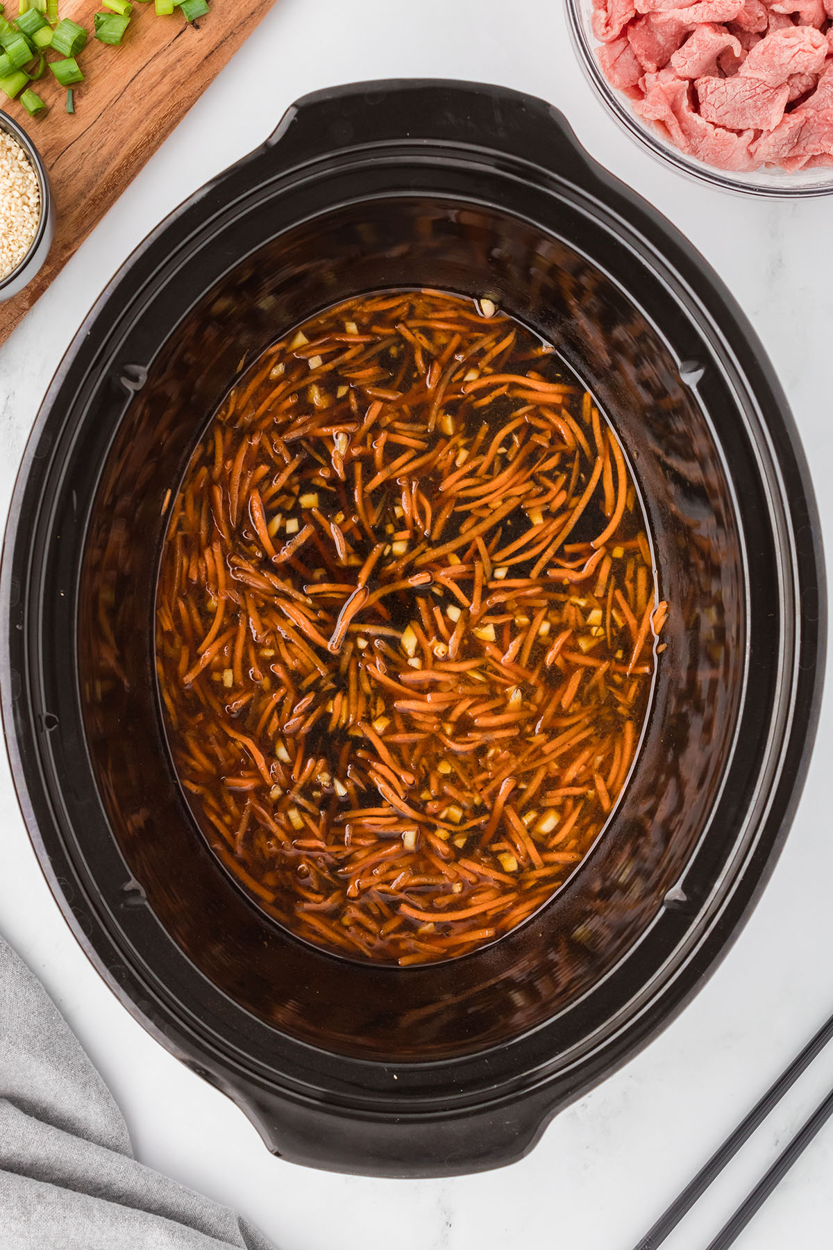 Shredded carrots added to the sauce in the slow cooker.