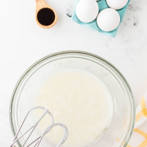 Vegetable oil, sugar, and sour cream in a glass mixing bowl.