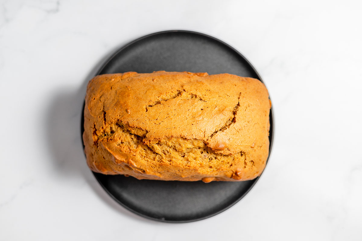Baked sweet potato bread on a black round platter.