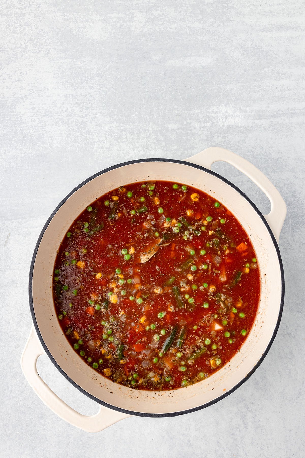 Hamburger Vegetable Soup ingredients are mixed together in a large pot and are ready to simmer on the stove.