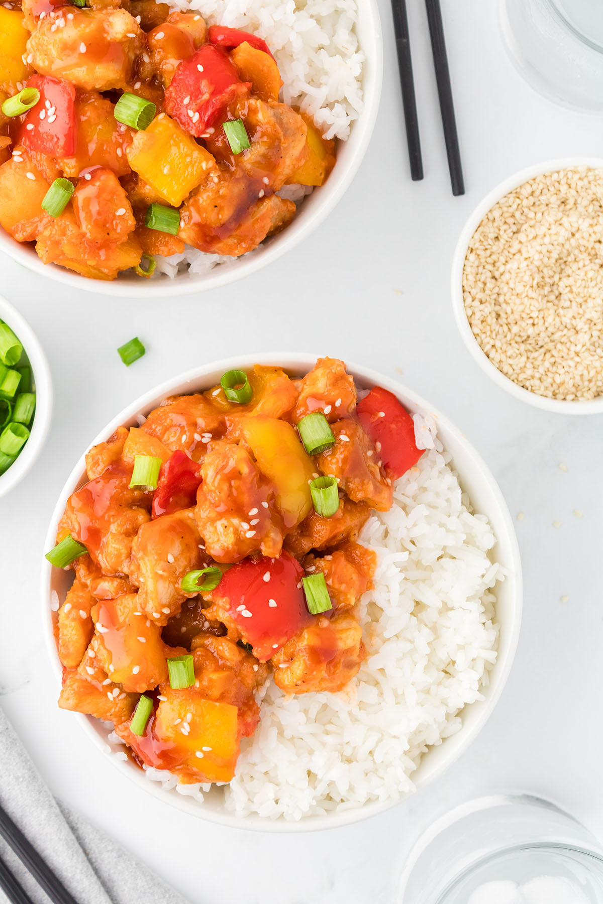 Sweet and sour chicken in a white bowl with white rice.