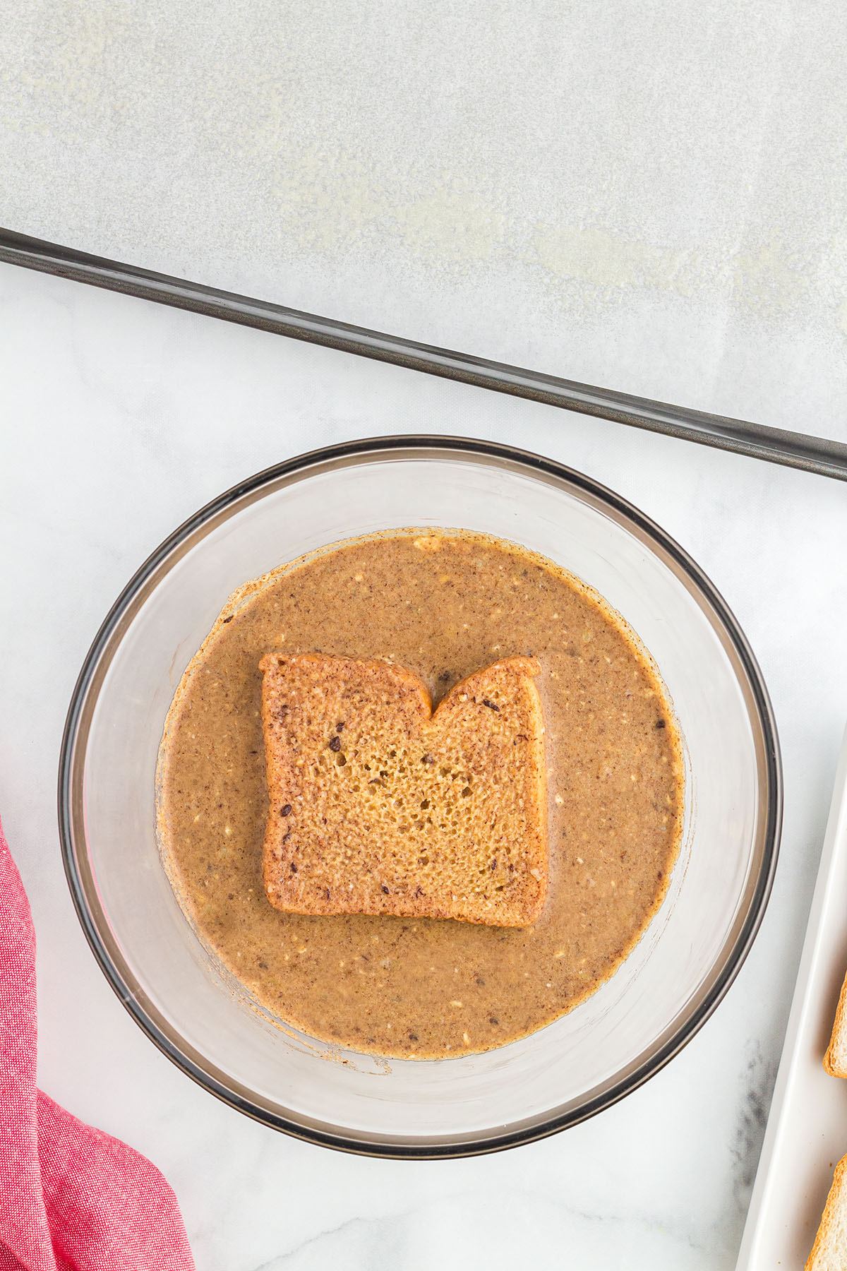 Bread dipped into the gingerbread mixture in the glass mixing bowl.
