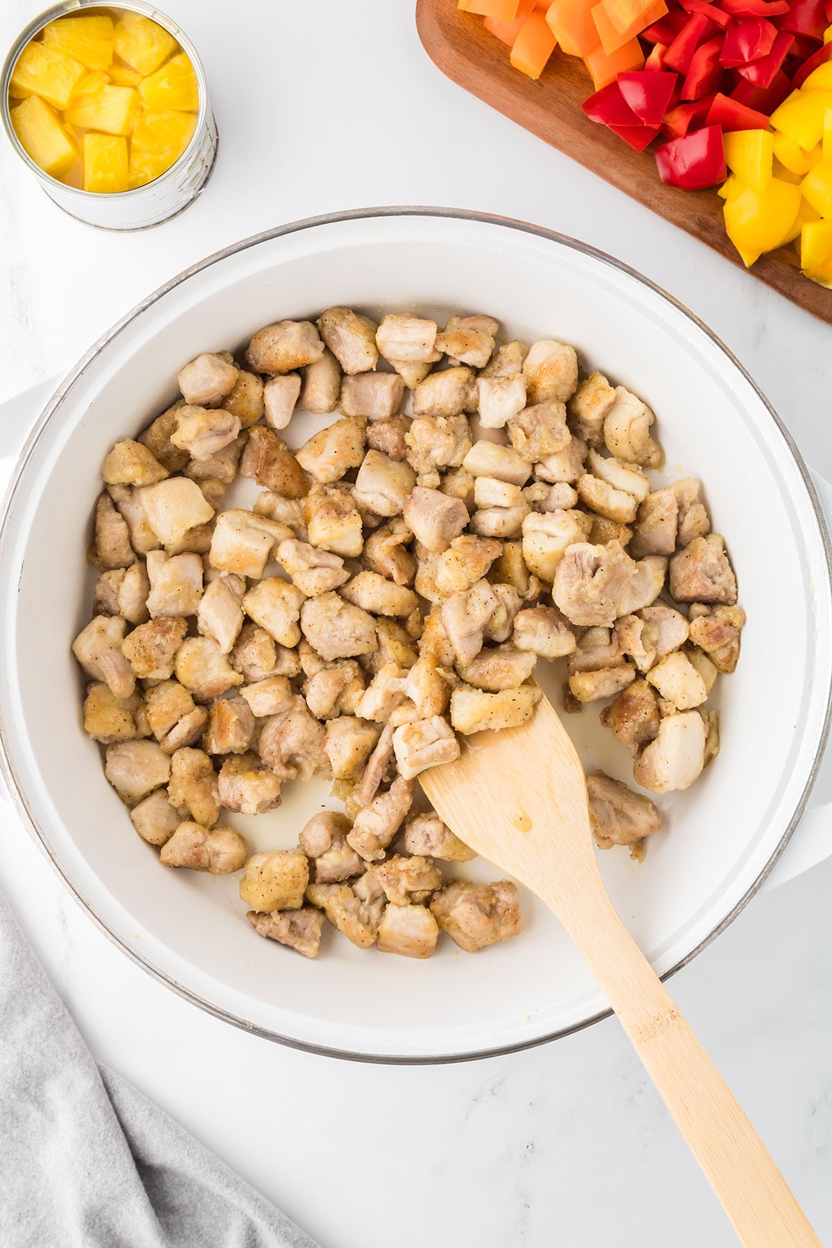 Chicken is browned in a large frying pan with oil.