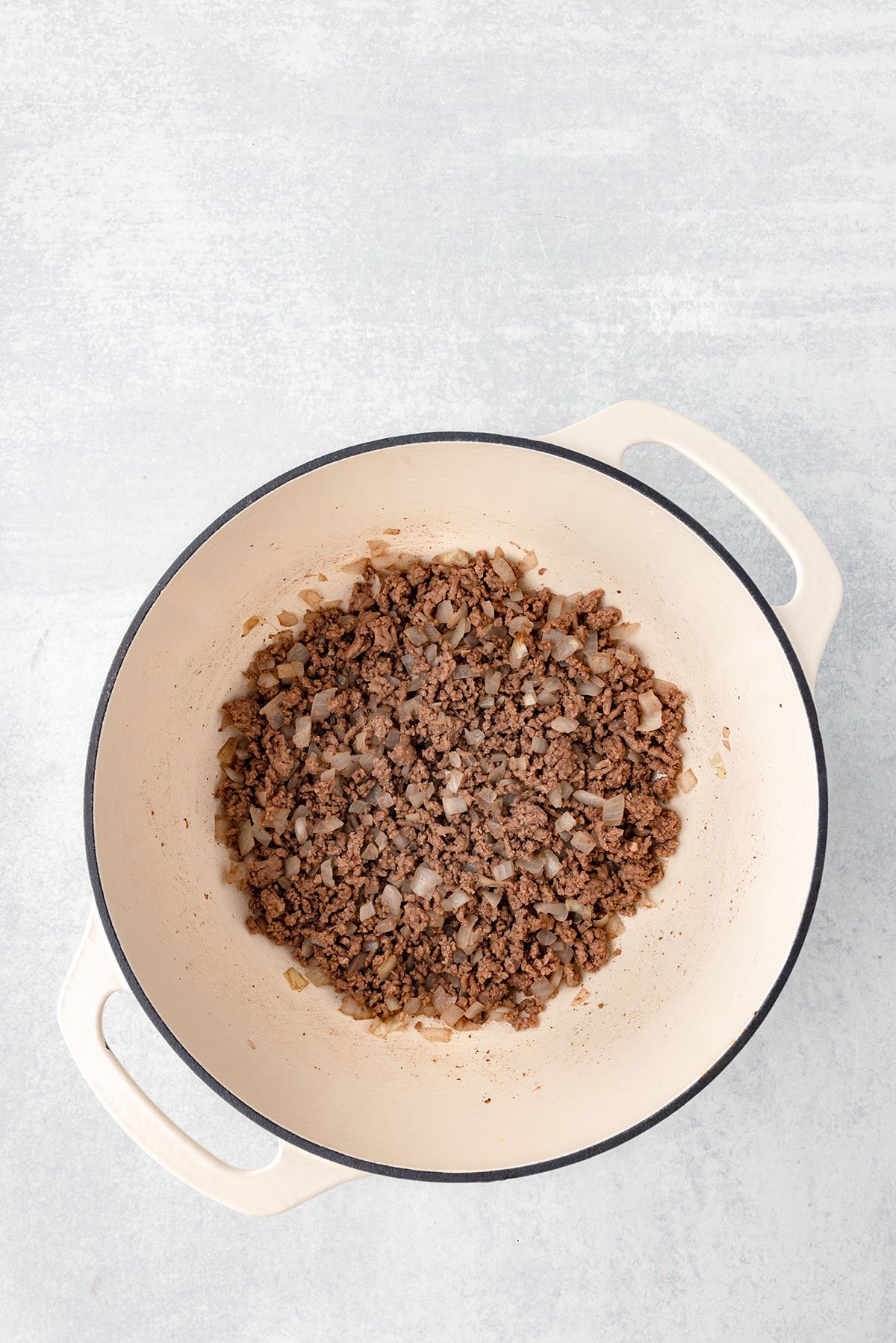 Cooked ground beef and diced onion in a large pot.