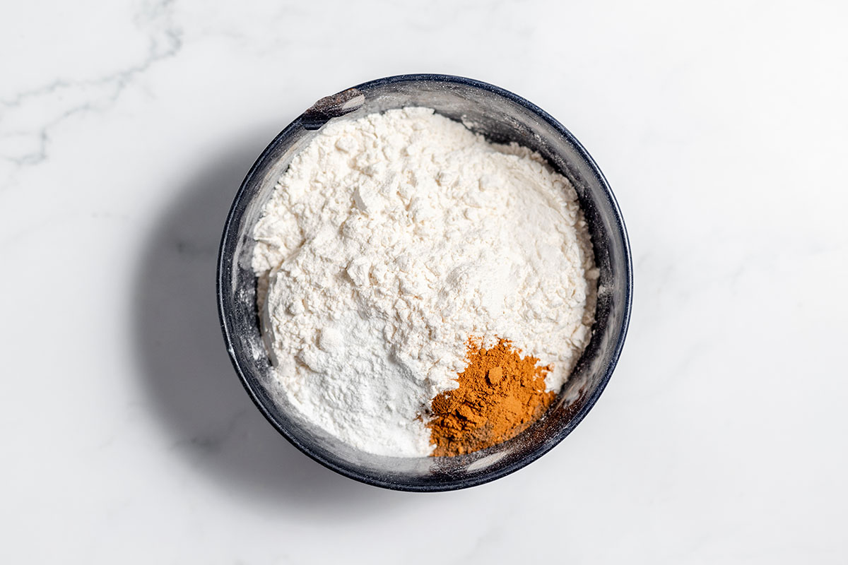 Flour, baking powder, baking soda, salt, cinnamon, cloves, and allspice in a bowl.