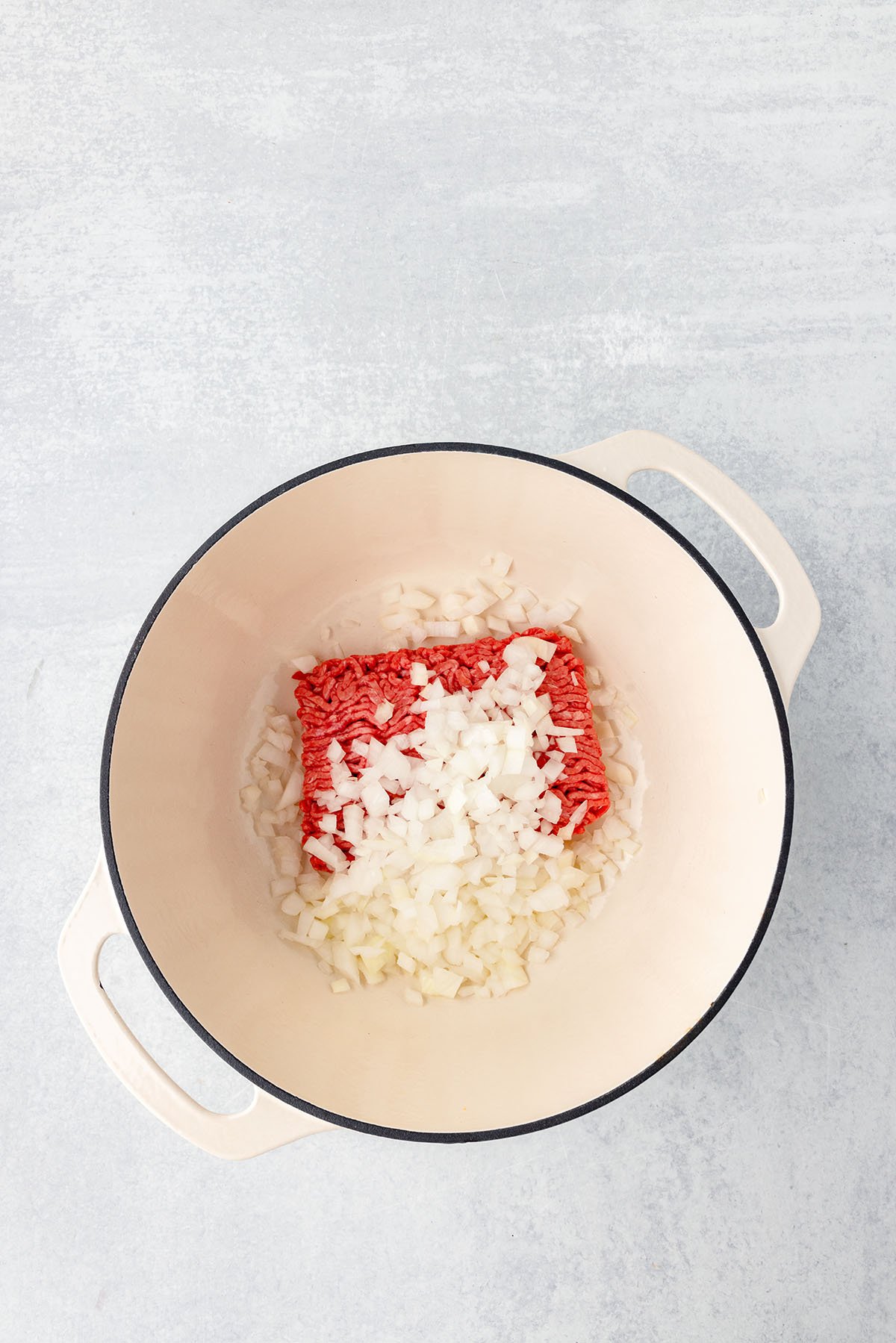 raw ground beef and diced onions in a large pot.