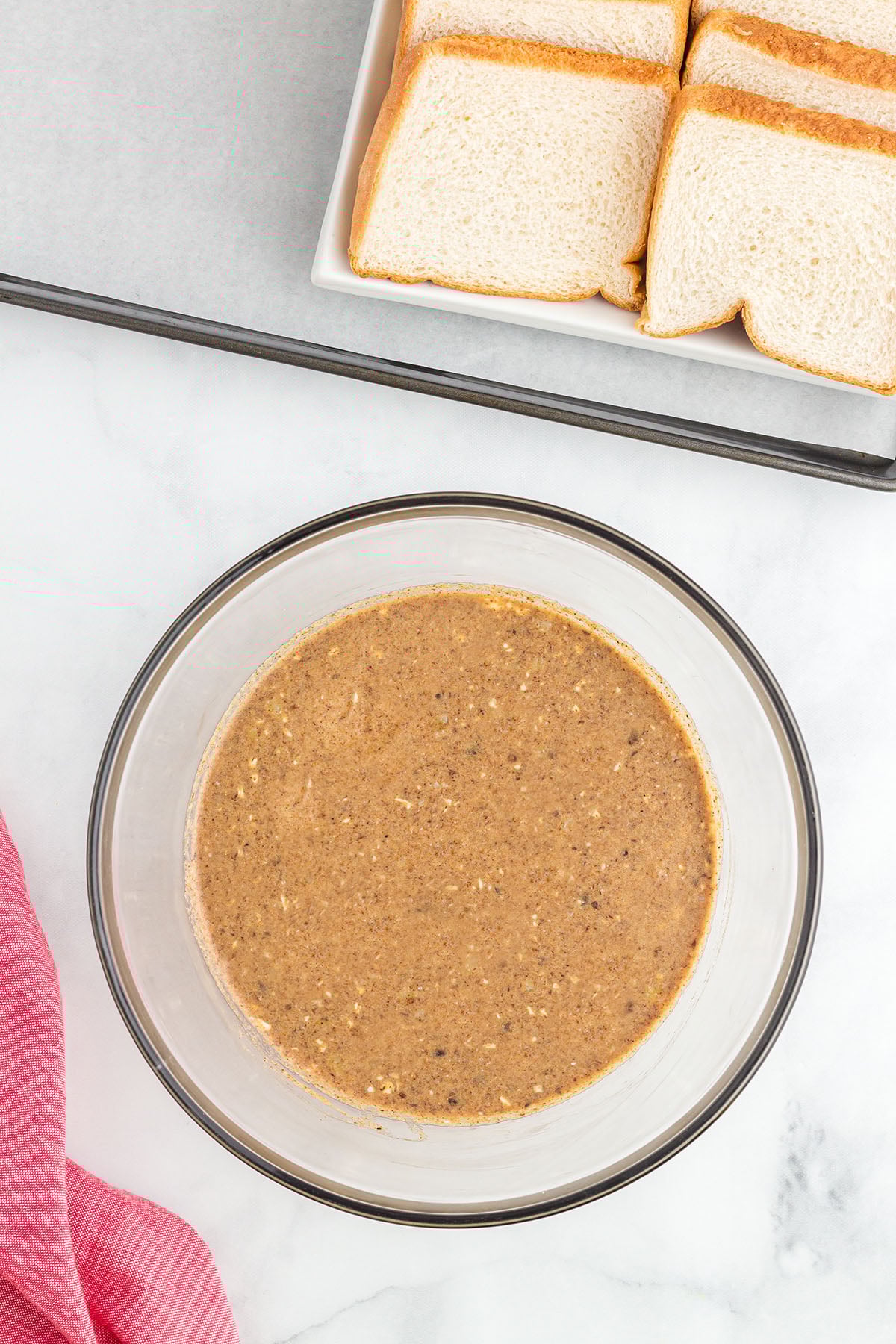 Milk and heavy cream are whisked into the egg and spice mixture in the glass mixing bowl.