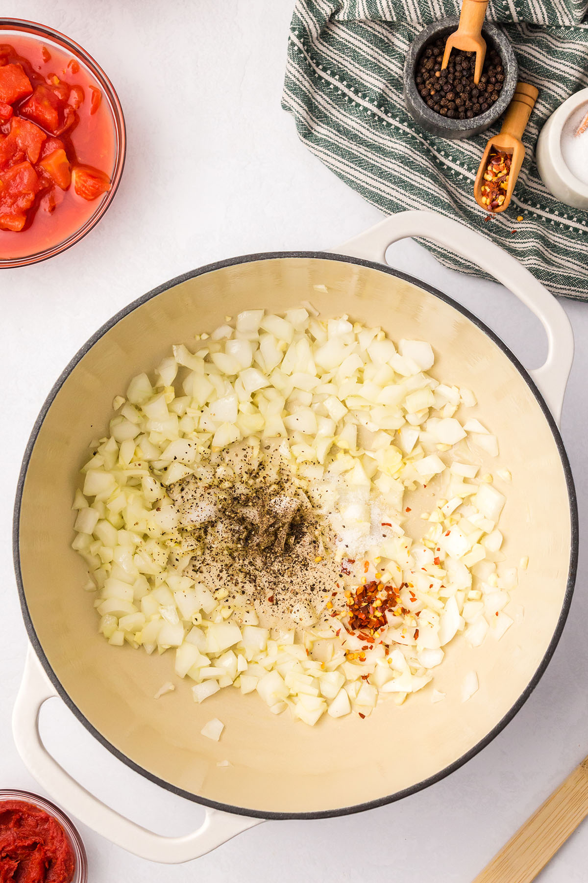 Salt, pepper, and red pepper flakes are added to the onion and garlic in the large pot.