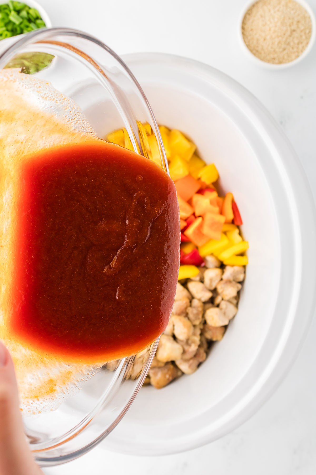 Sweet and sour sauce poured over the chicken, bell peppers, and pineapple in the slow cooker.